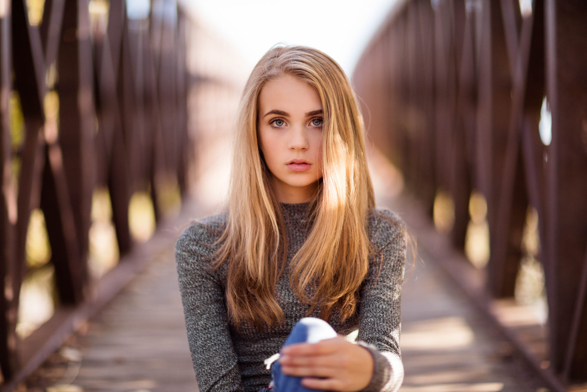 Blonde girl with blue eyes sitting on a bridge HD Wallpaper