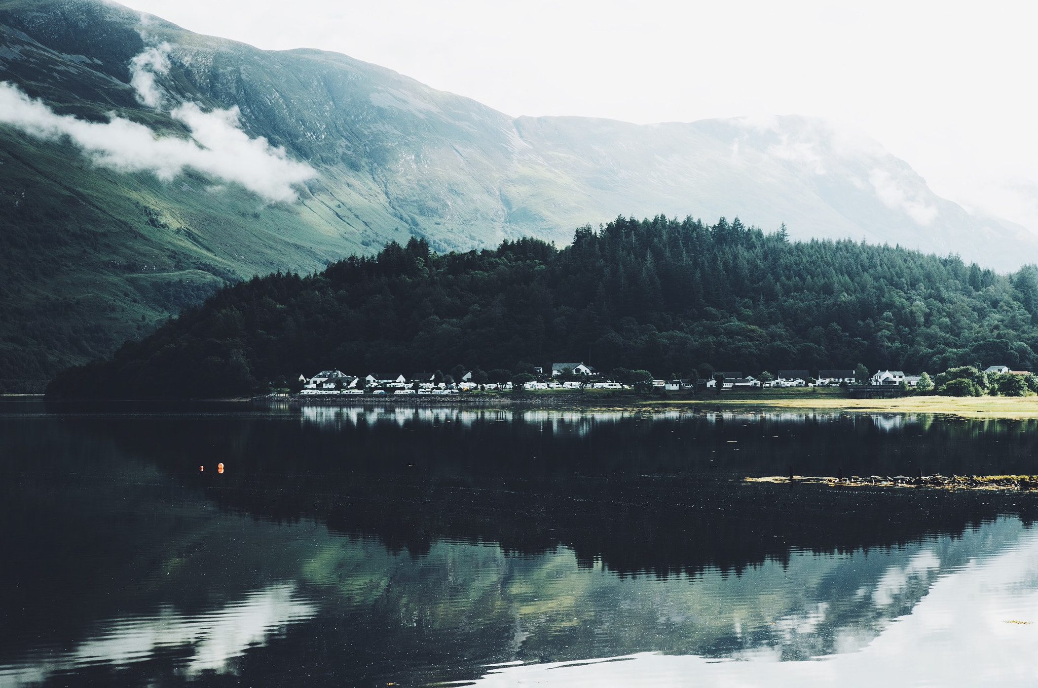Village by a lake with mountains and mist HD Wallpaper