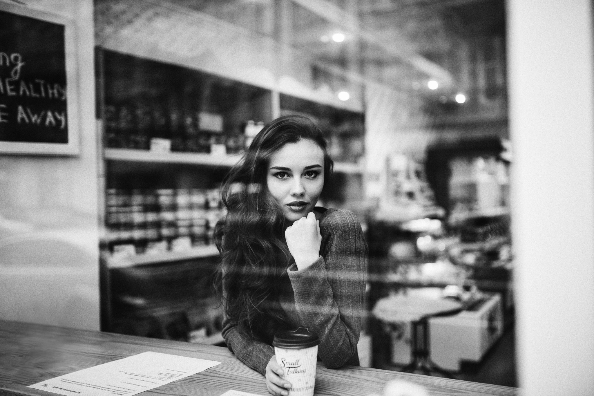 Woman with coffee cup looking through window HD Wallpaper