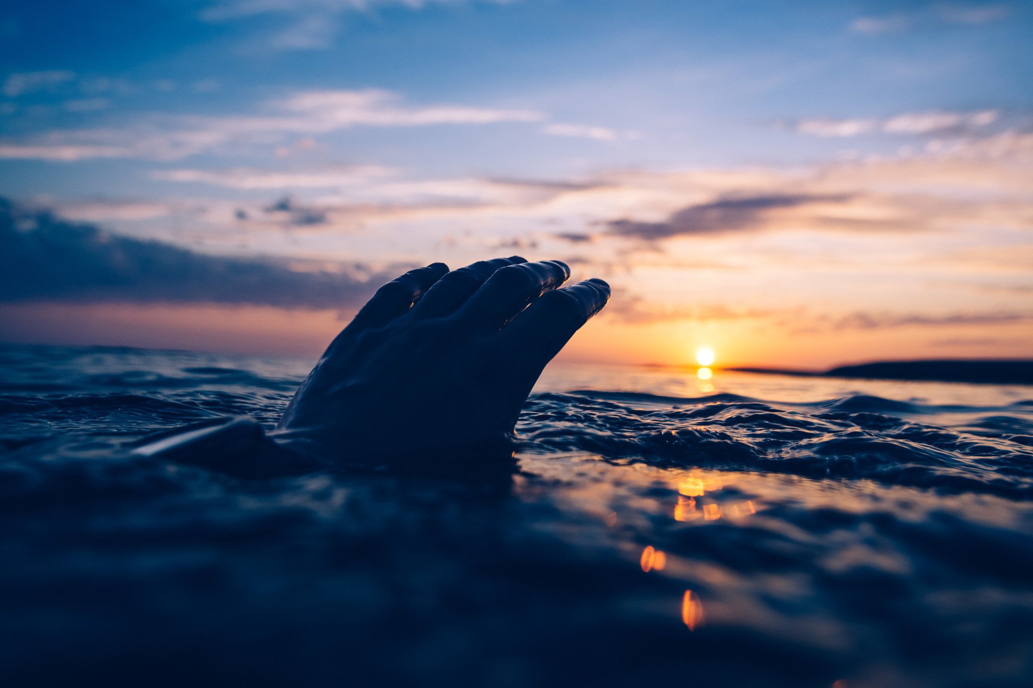 Hand reaching out of the sea at sunset HD Wallpaper
