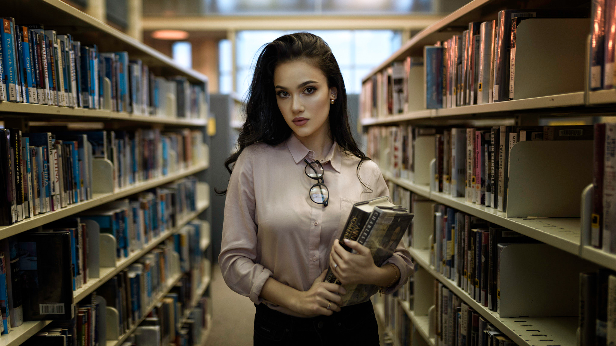 Woman holding books in a library HD Wallpaper