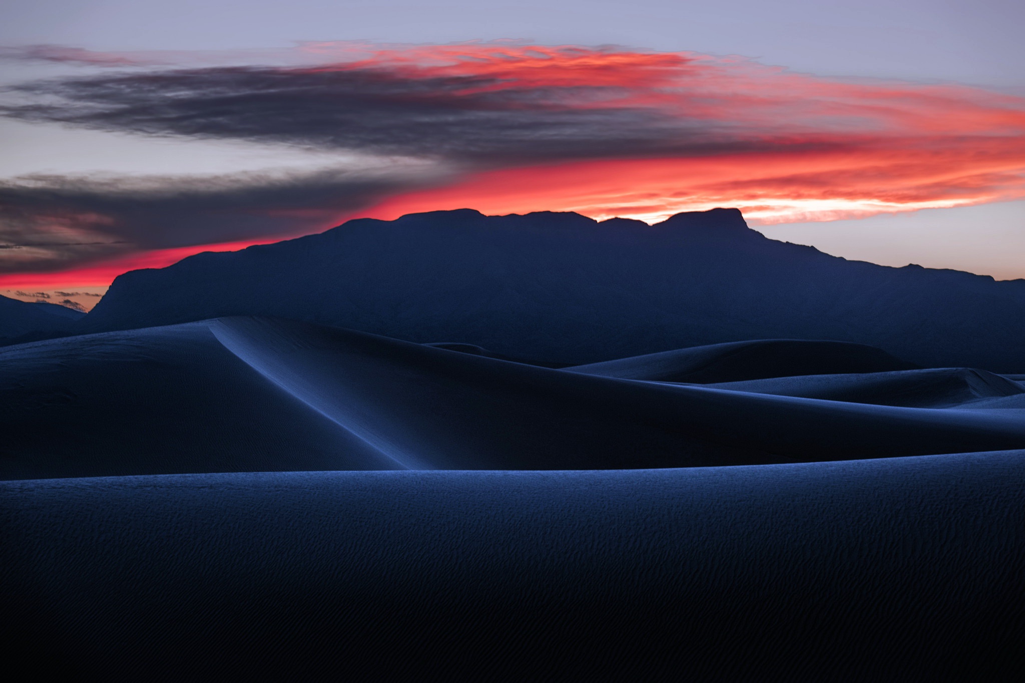 Dark sand dunes at sunset with mountain silhouette HD Wallpaper