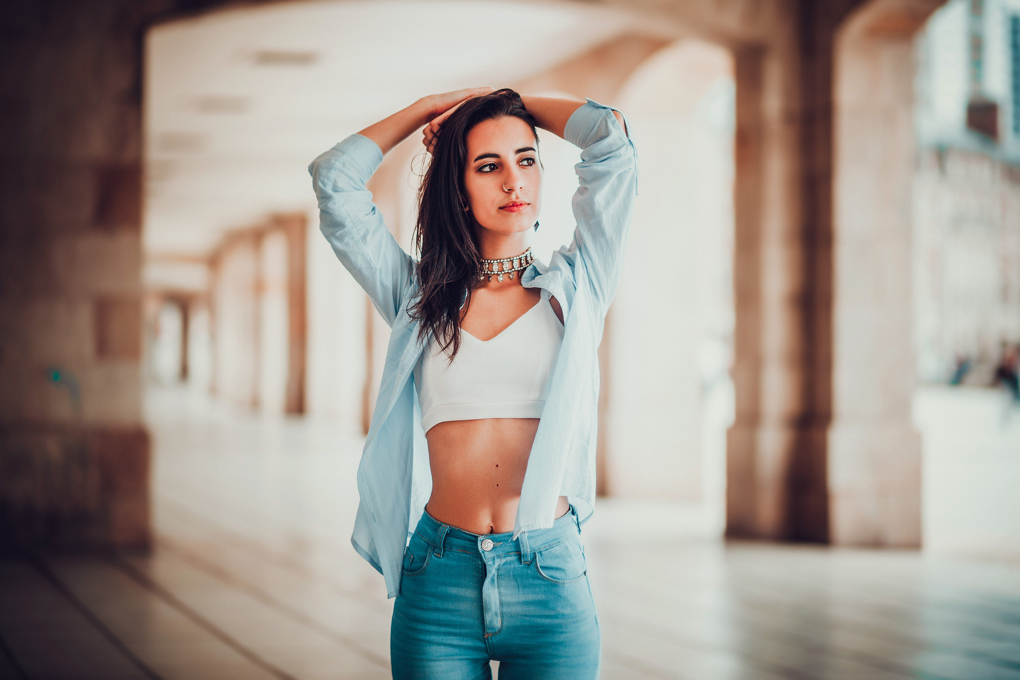 Woman in blue shirt and jeans with hands on head HD Wallpaper