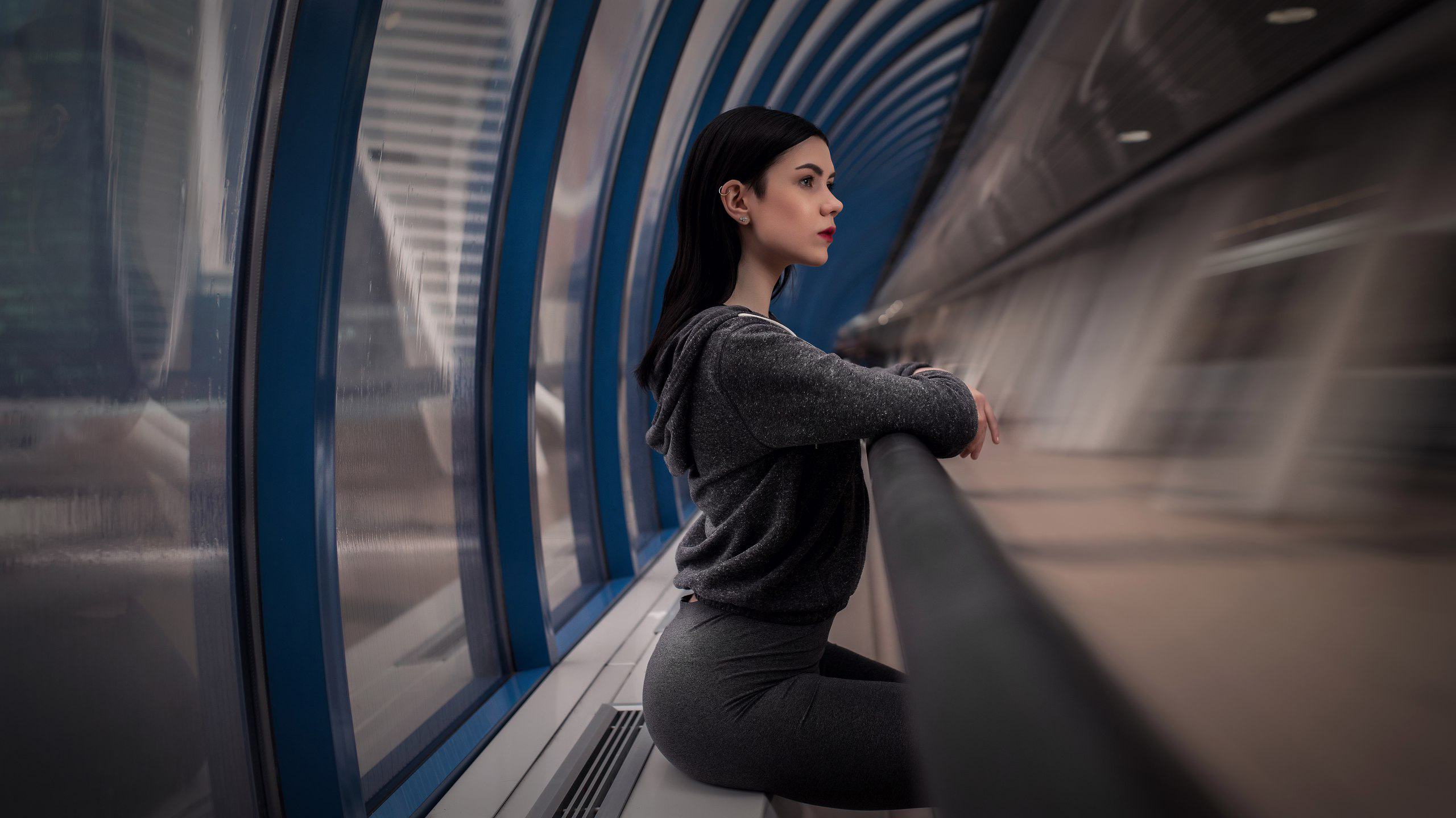 Woman in grey clothing sitting in a futuristic tunnel HD Wallpaper