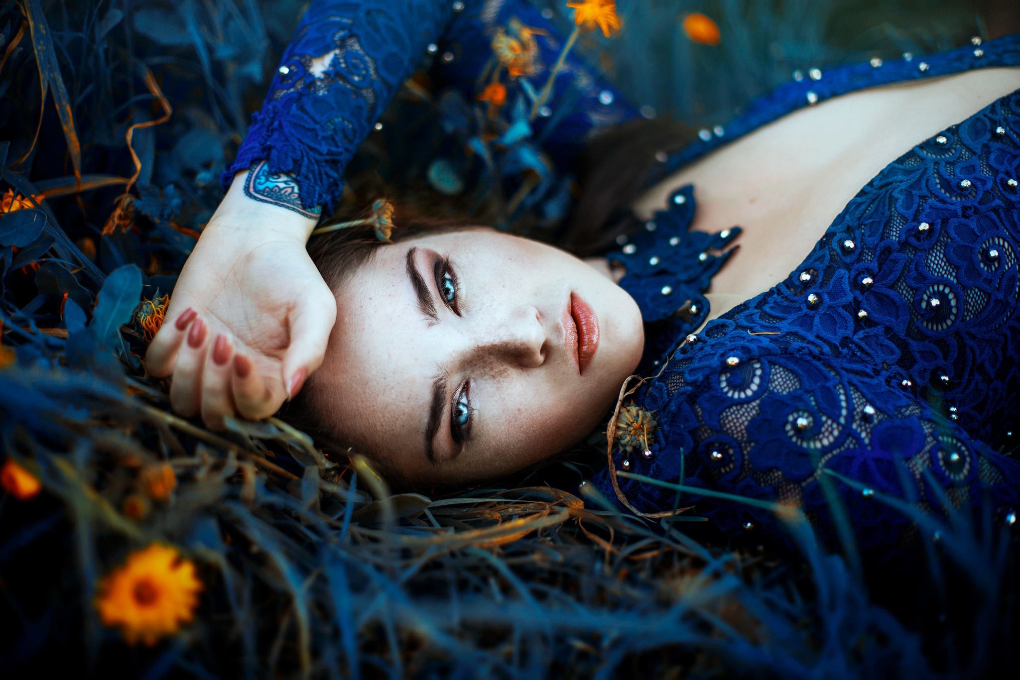 Woman with blue eyes and tattoo lying down HD Wallpaper