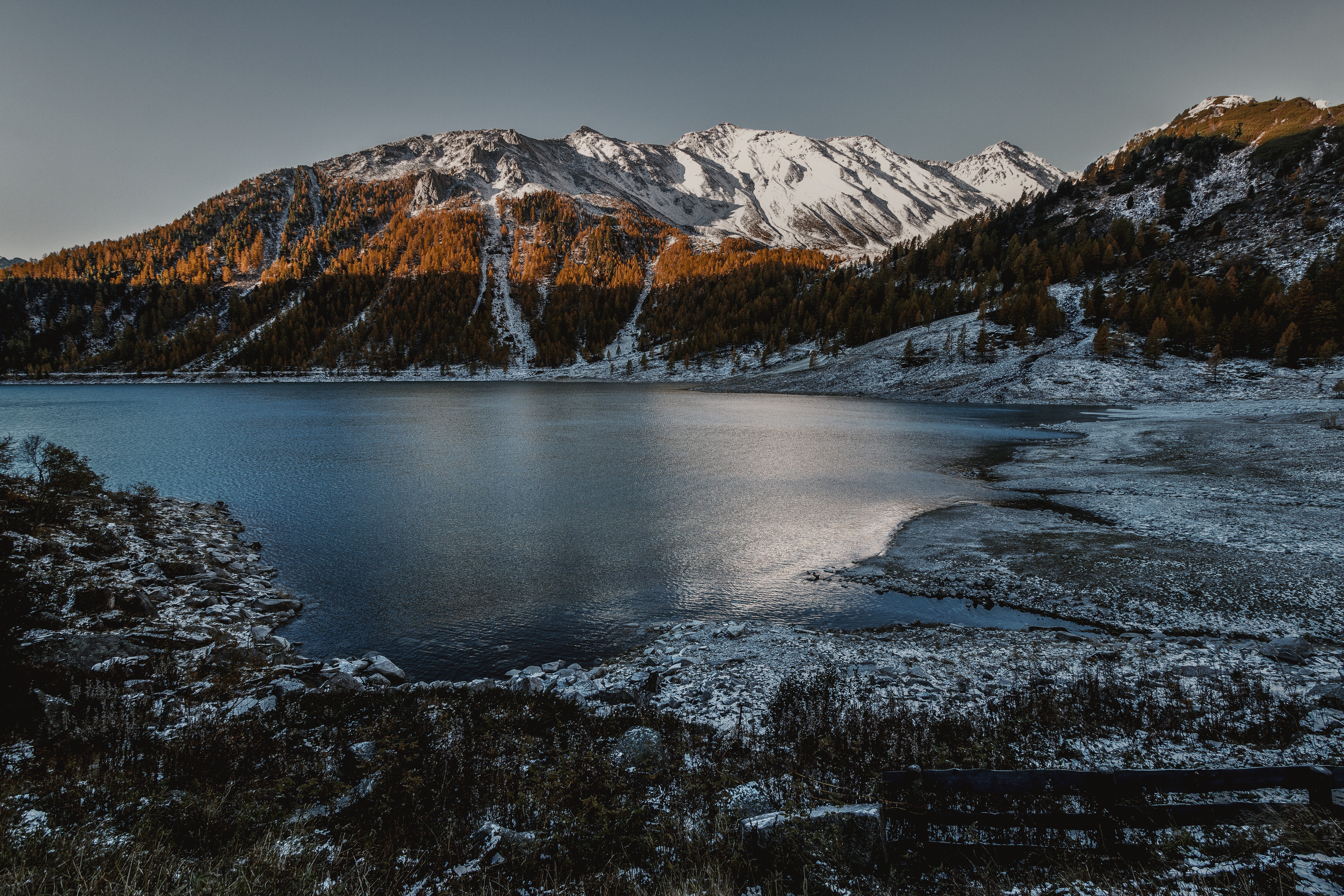 Snow-capped mountains overlooking a lake with autumn trees HD Wallpaper