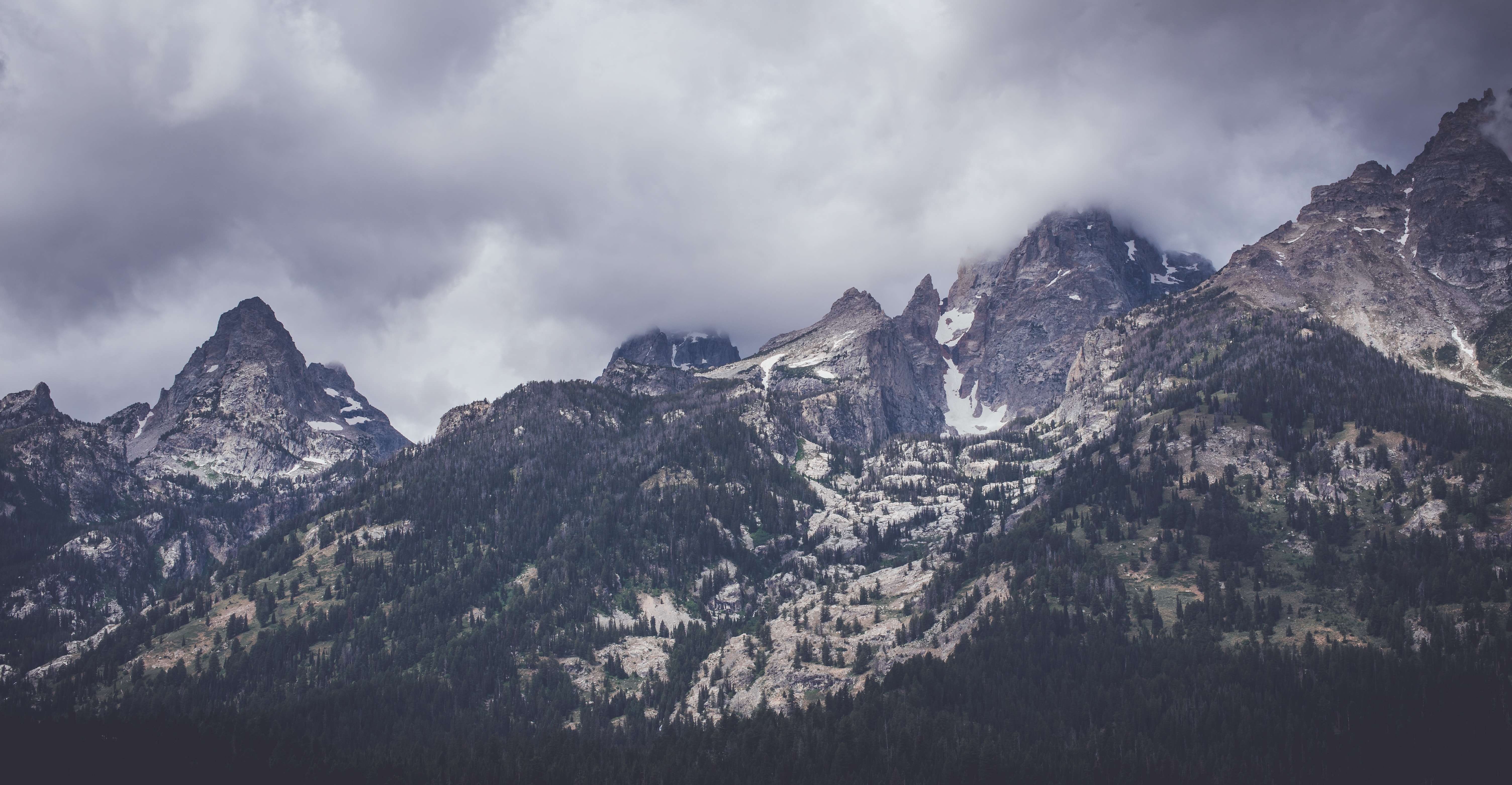Jagged mountain peaks under a cloudy sky HD Wallpaper