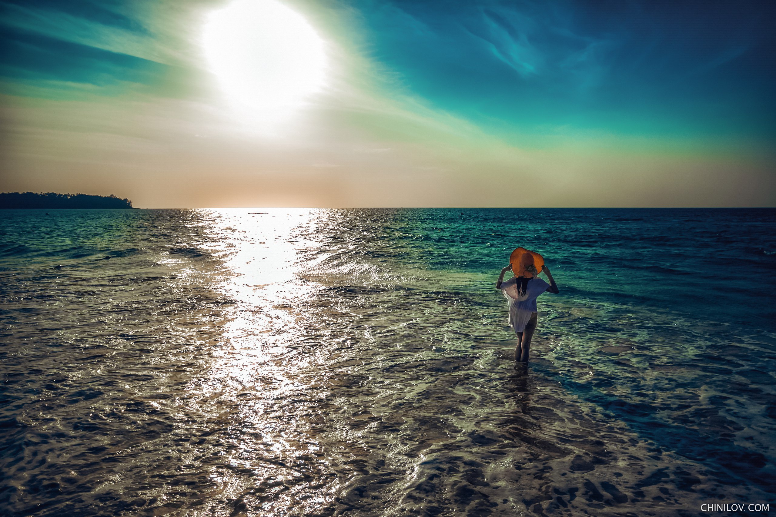 Woman in hat walking into the sea at sunset HD Wallpaper
