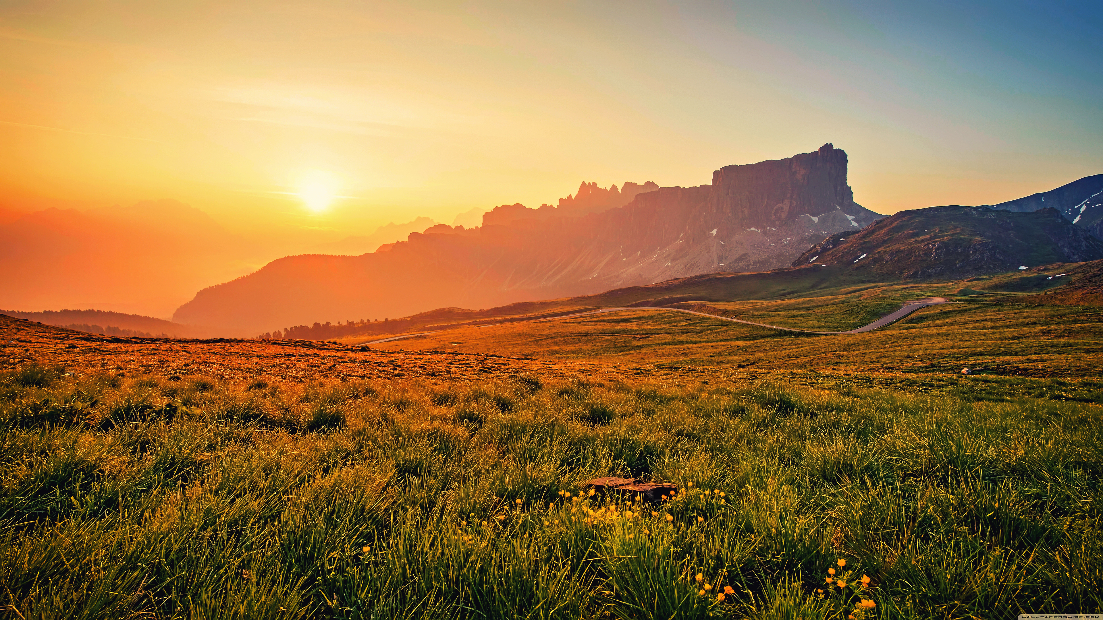 Sunset over a grassy mountain landscape HD Wallpaper