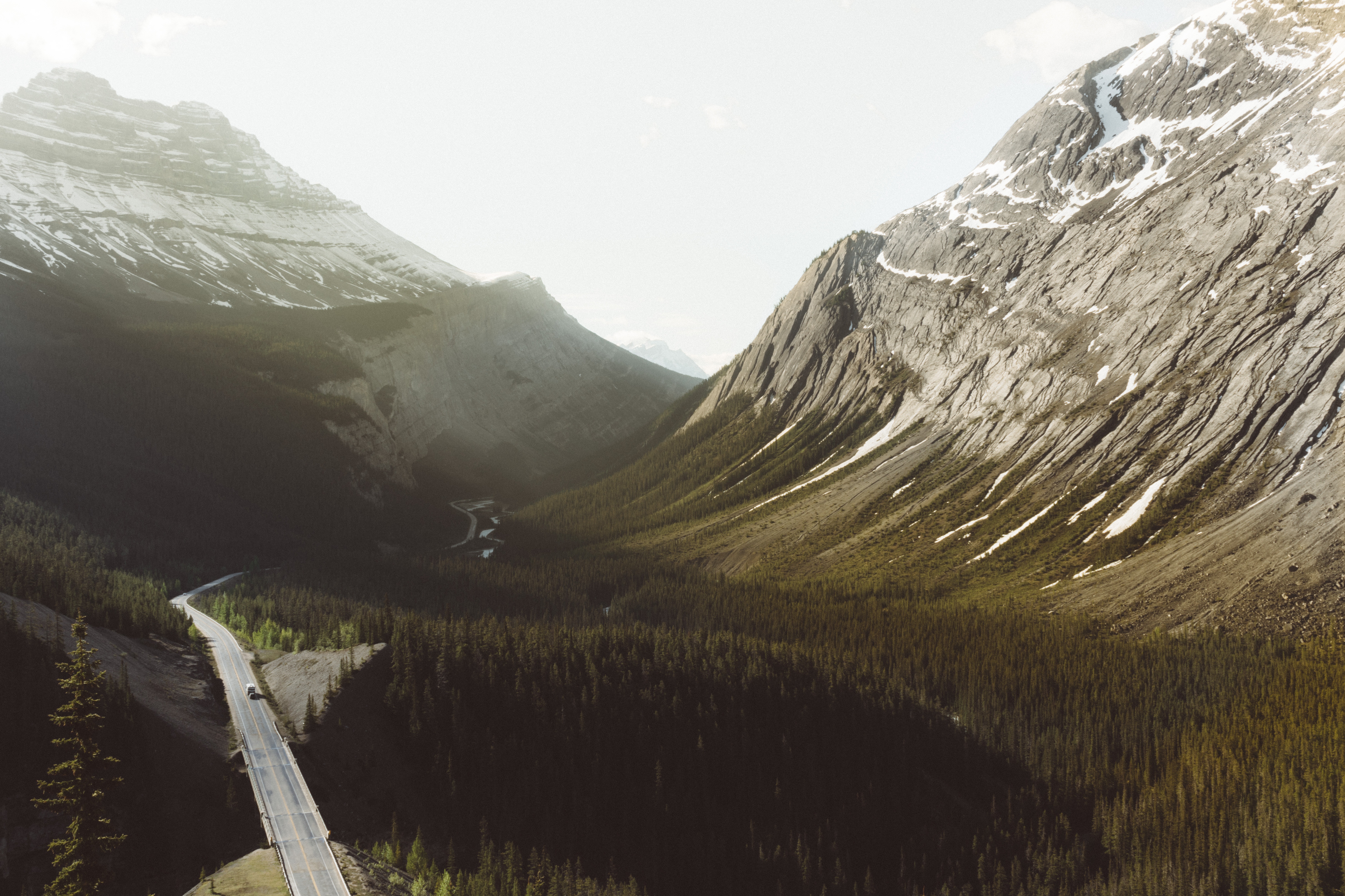 Road through a mountain valley with a forest HD Wallpaper