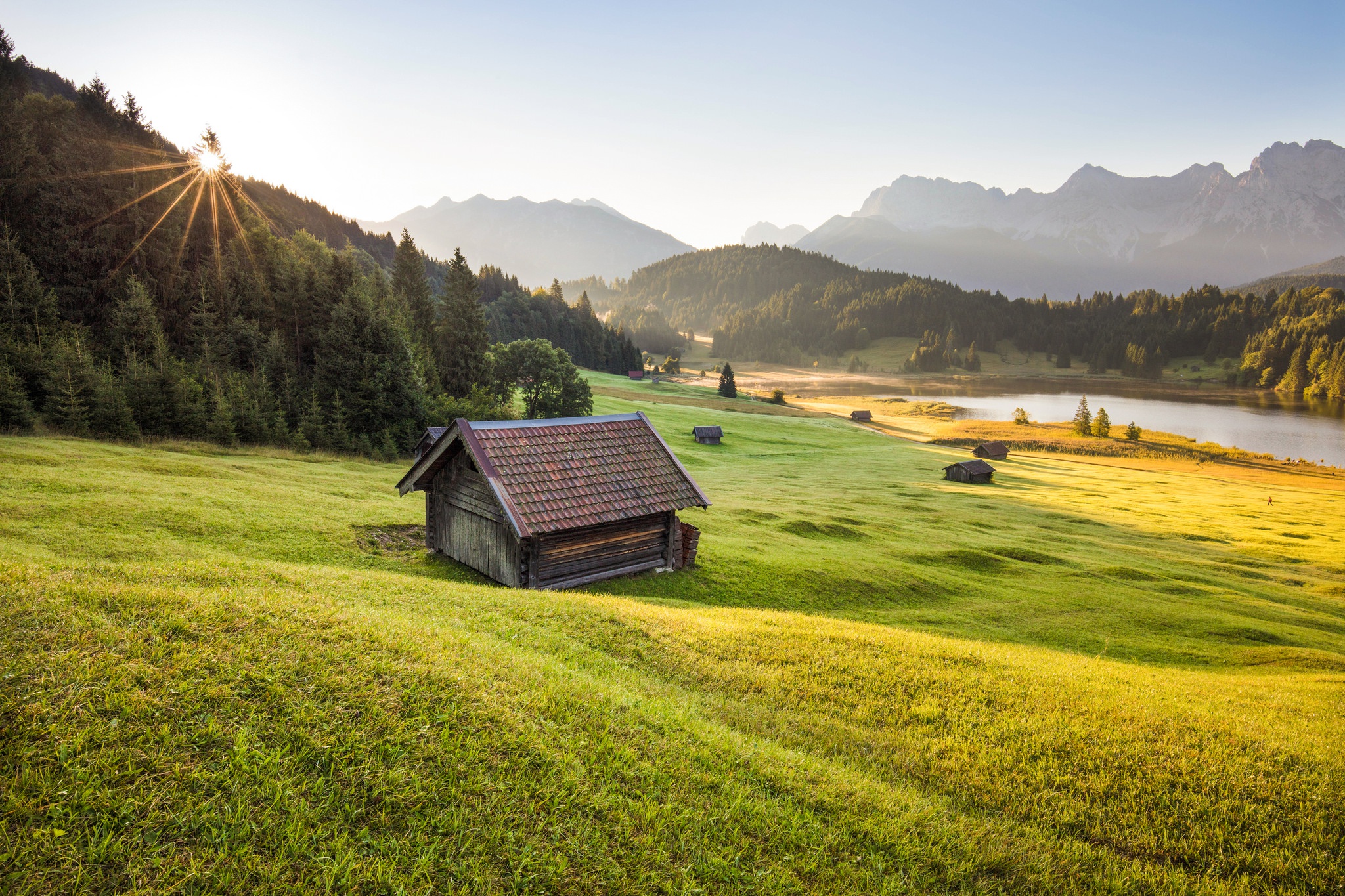 Wooden cabin in a green meadow with mountains and lake HD Wallpaper