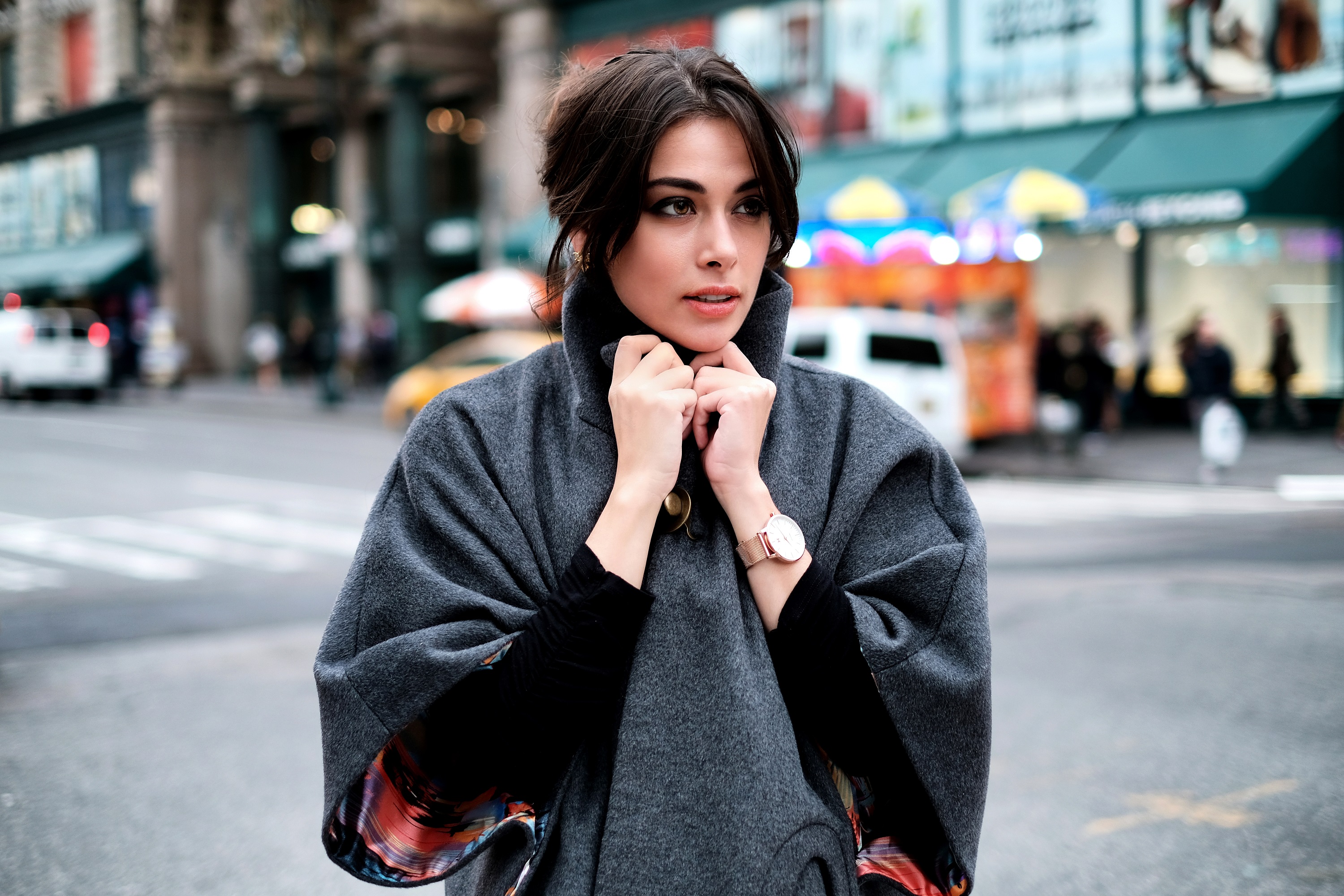 Woman in a gray cape on a city street HD Wallpaper