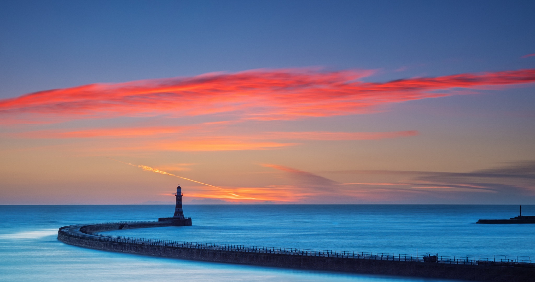 Lighthouse on a pier at sunset with colorful clouds HD Wallpaper
