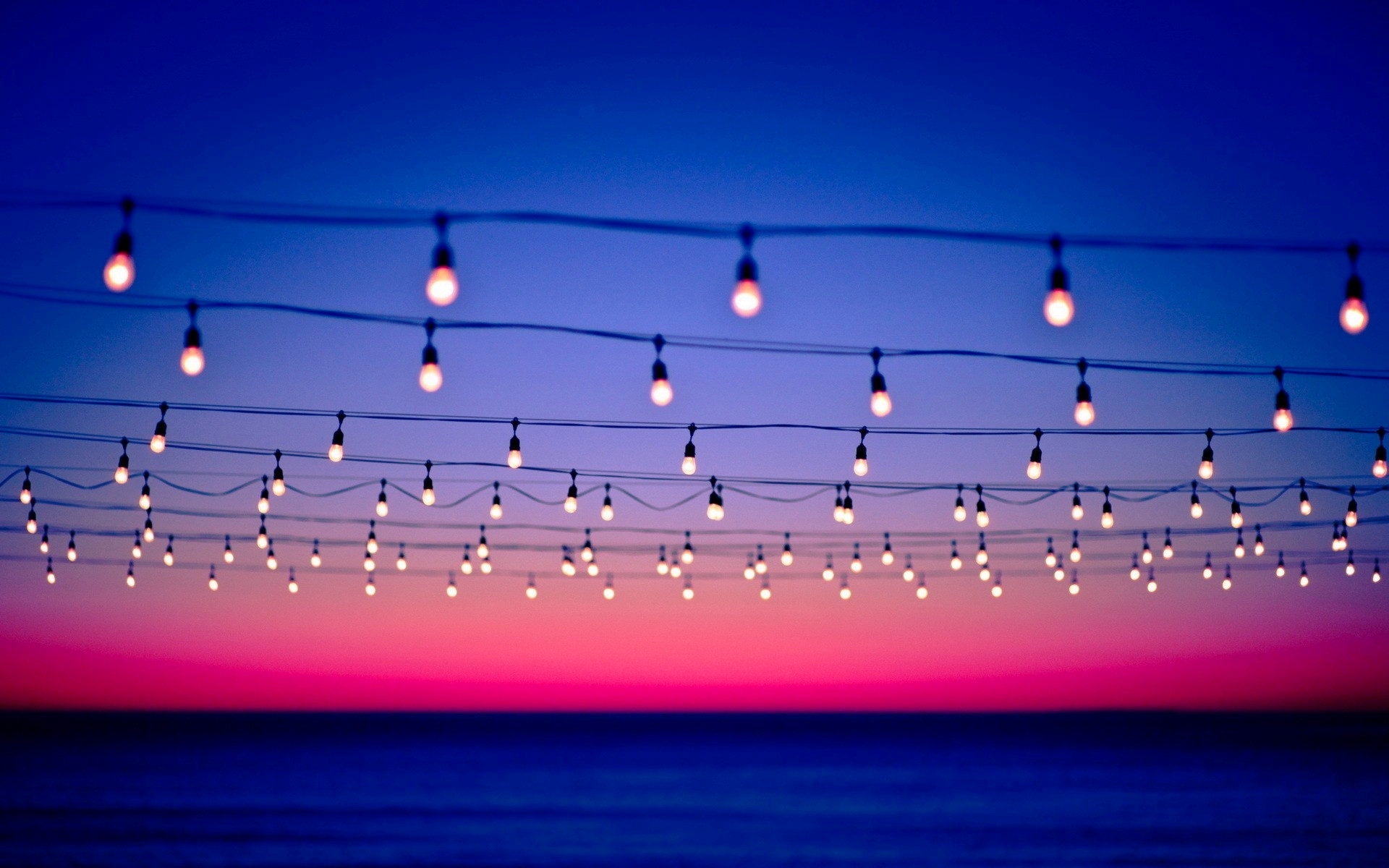 String lights over the ocean at sunset HD Wallpaper
