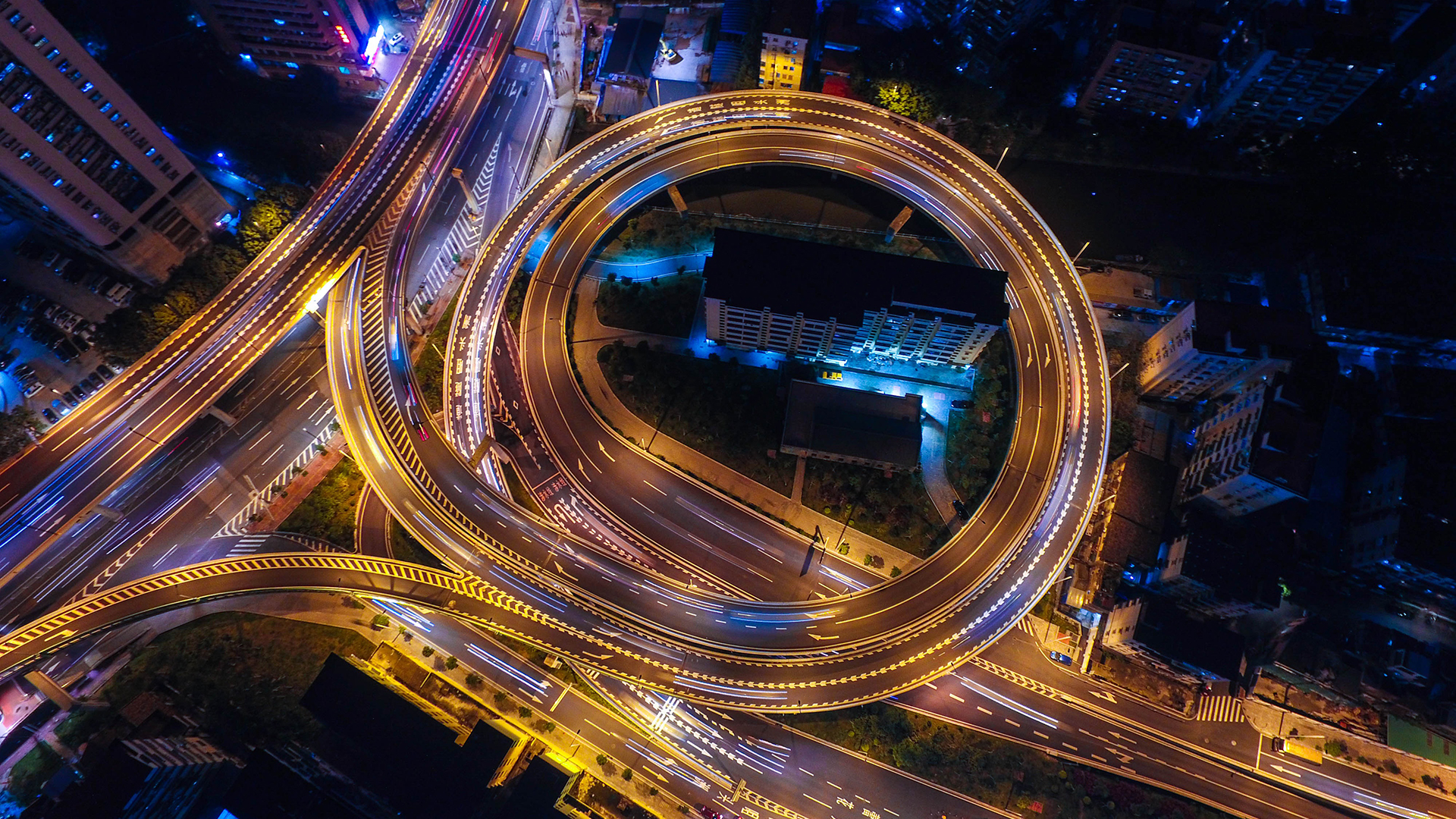 Aerial view of a busy highway interchange at night HD Wallpaper