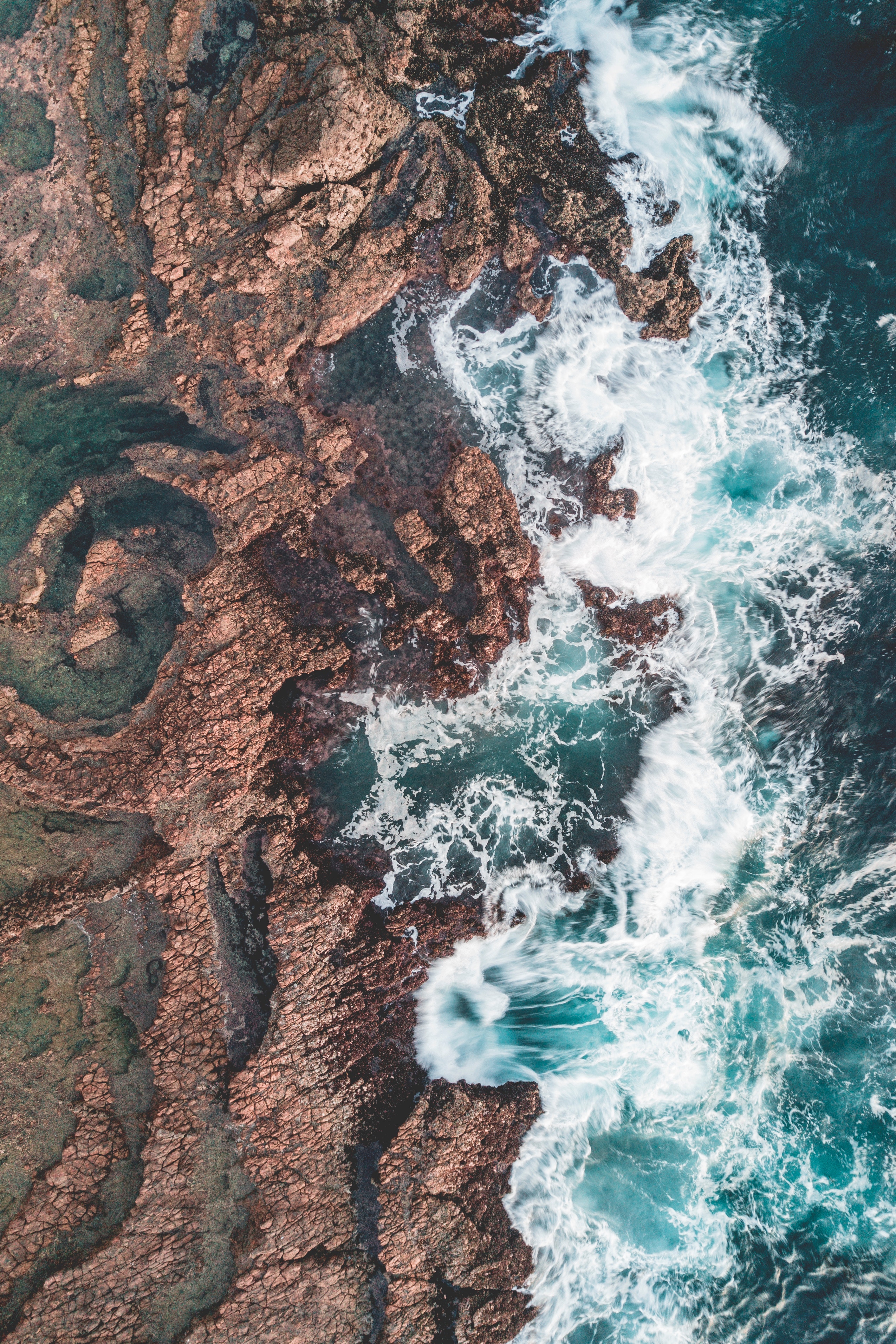 Aerial view of ocean waves crashing on rocky shore HD Wallpaper