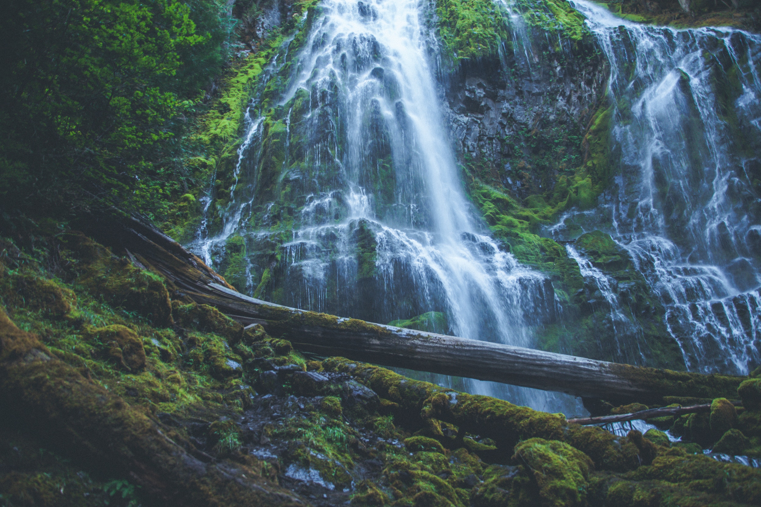 Mossy waterfall cascading over rocks with fallen log HD Wallpaper