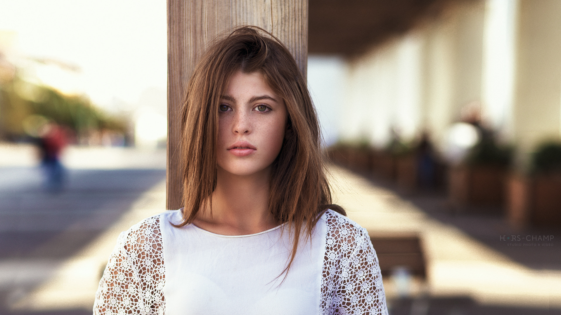 Woman with freckles leaning on a wooden post HD Wallpaper