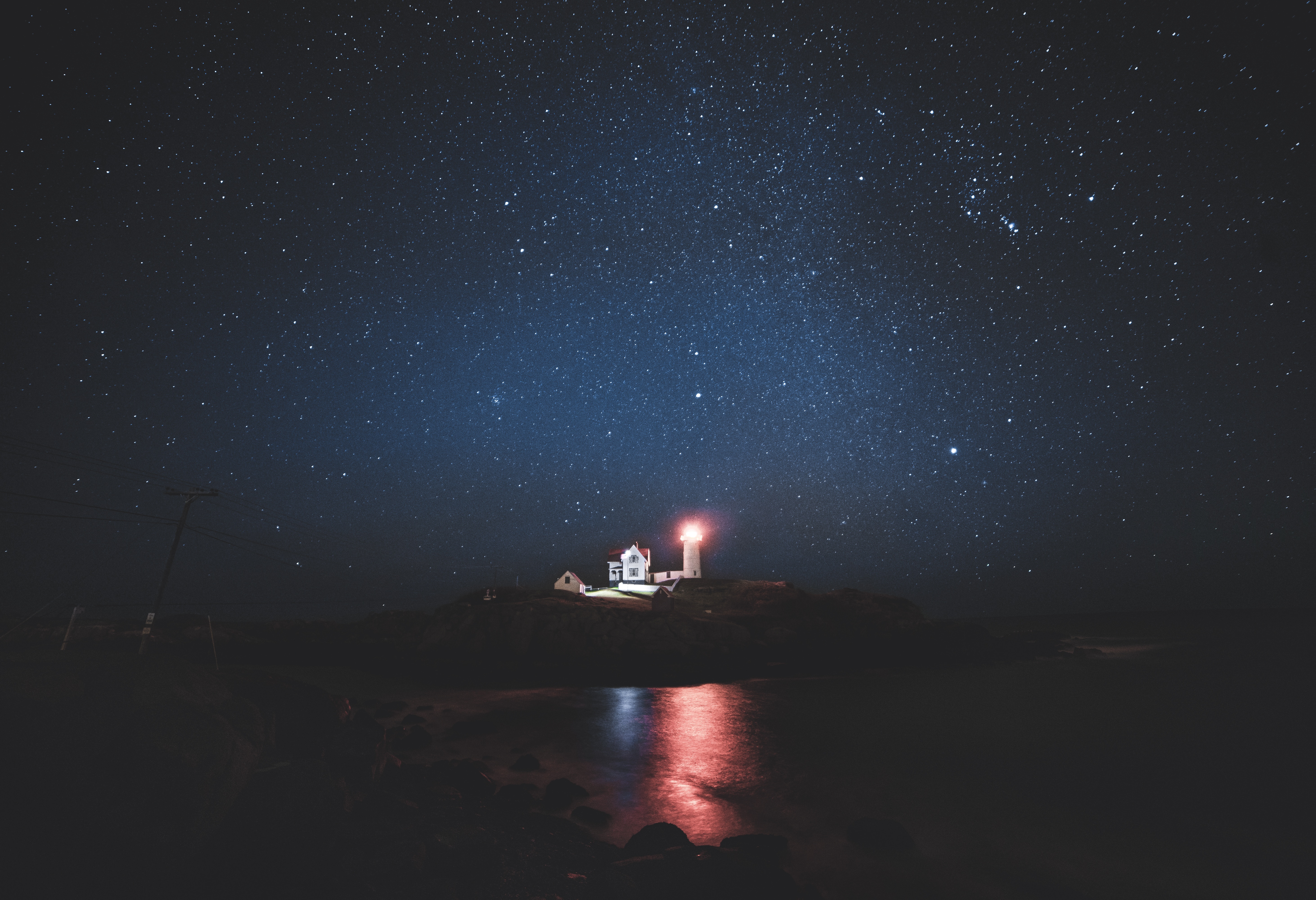 Lighthouse under a starry night sky HD Wallpaper