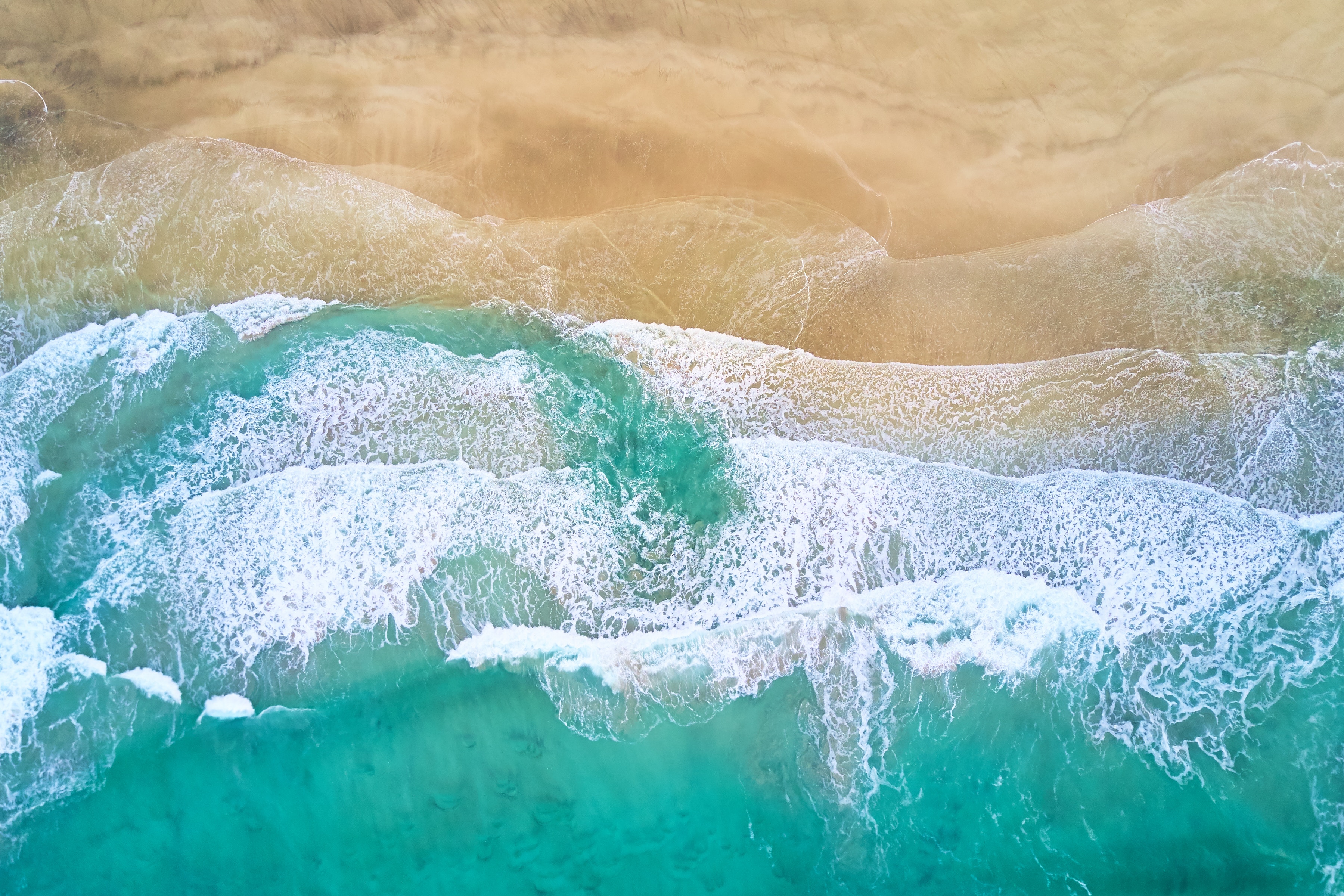 Aerial view of a sandy beach with turquoise waves HD Wallpaper