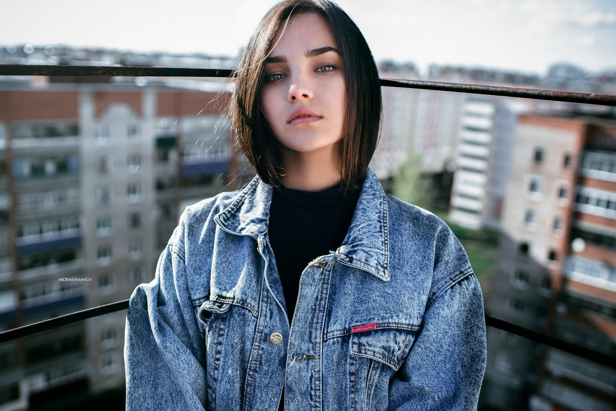 Woman in denim jacket on rooftop with buildings in background HD Wallpaper
