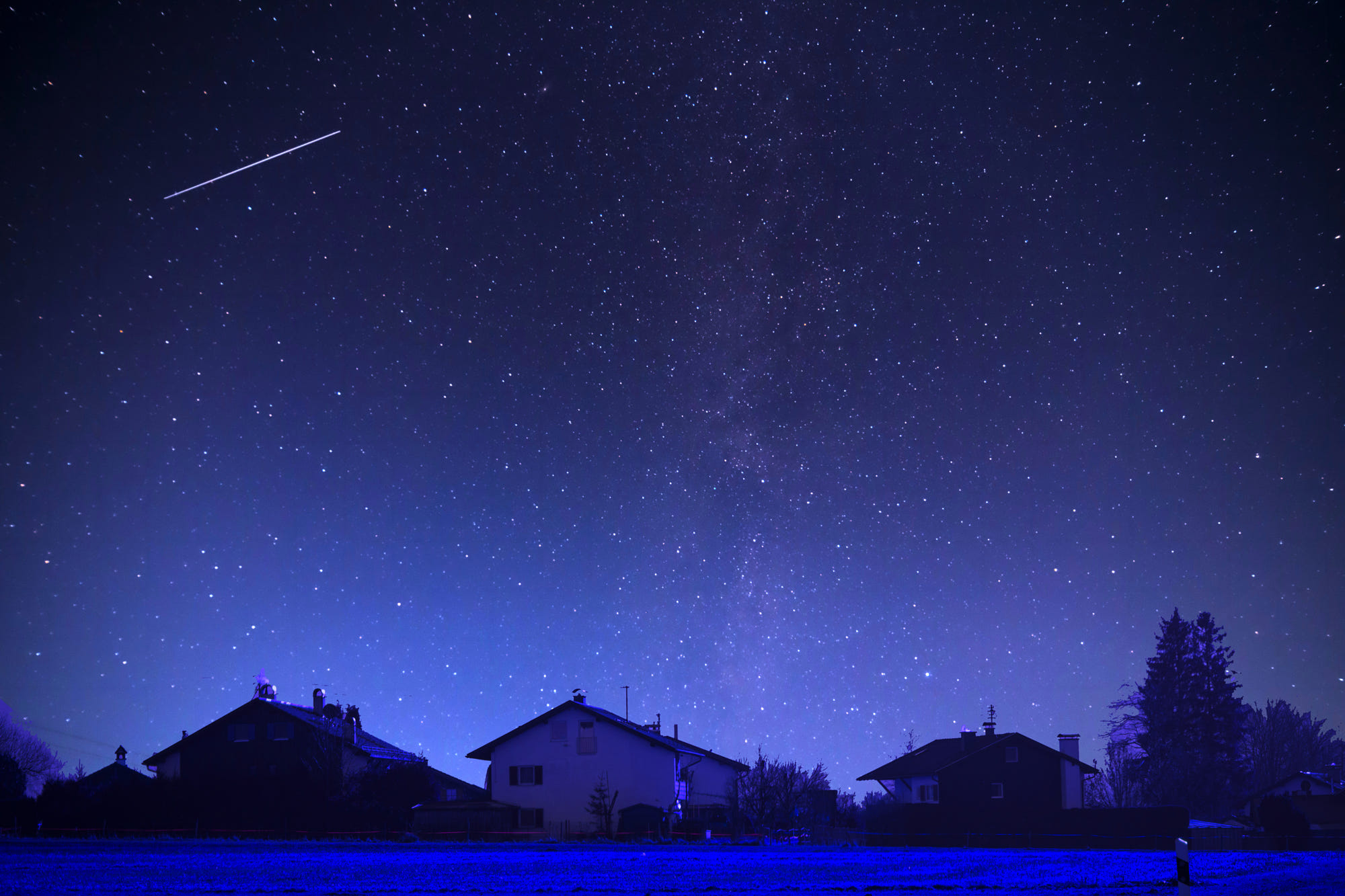 Starry night sky over houses with a meteor shower HD Wallpaper