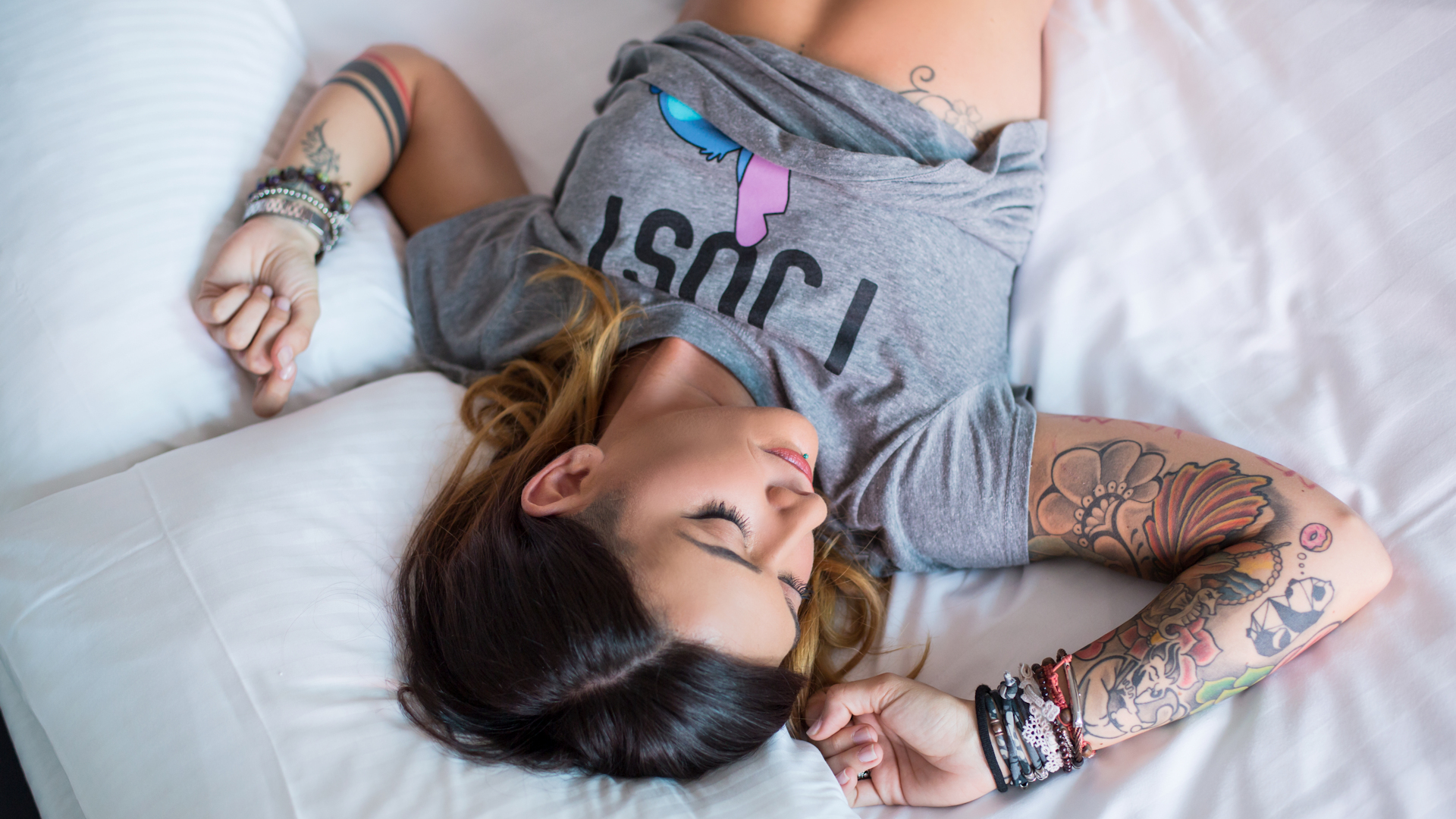 Woman with tattoos lying on a bed HD Wallpaper