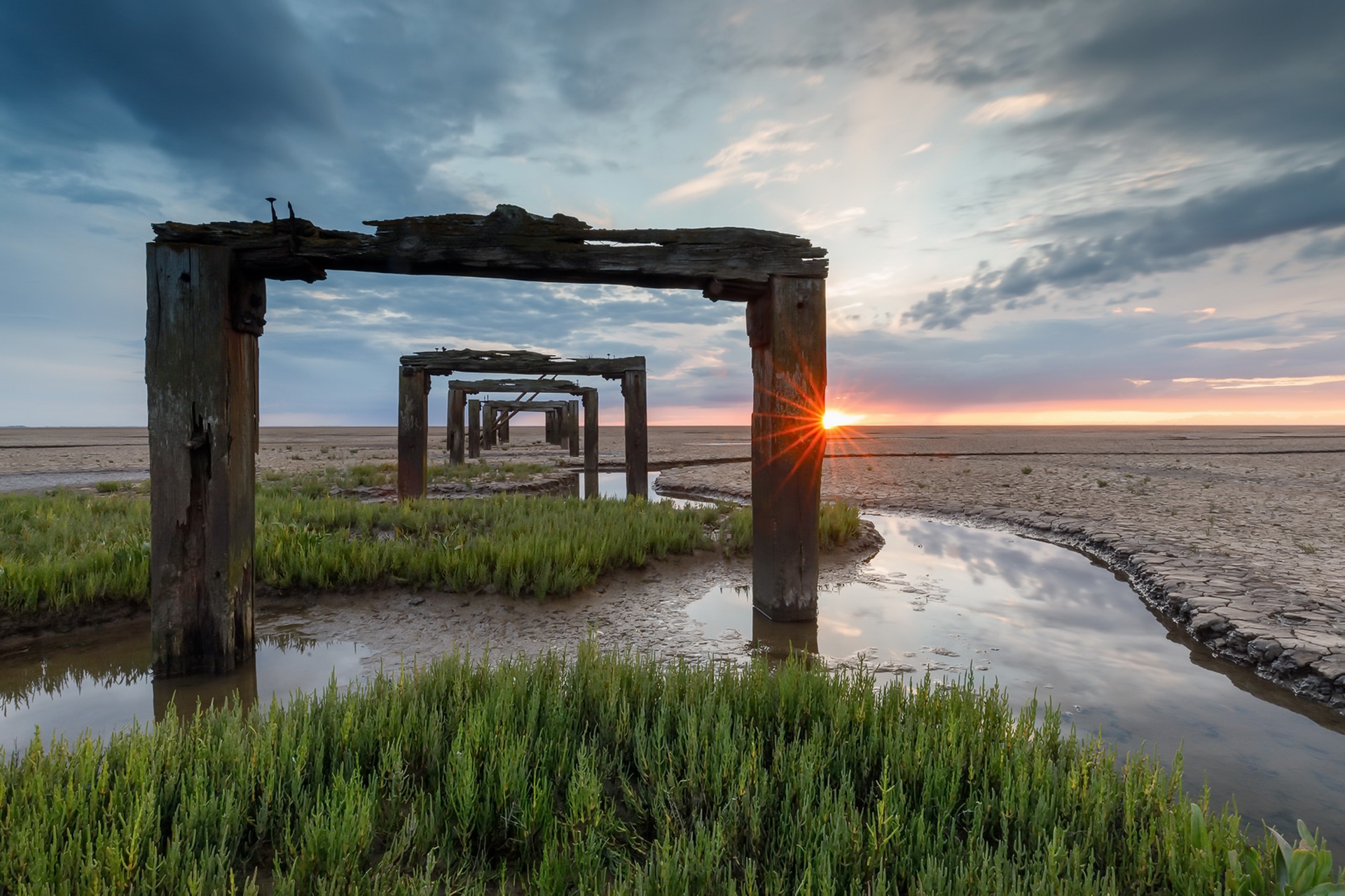 Wooden structures on a beach at sunset HD Wallpaper