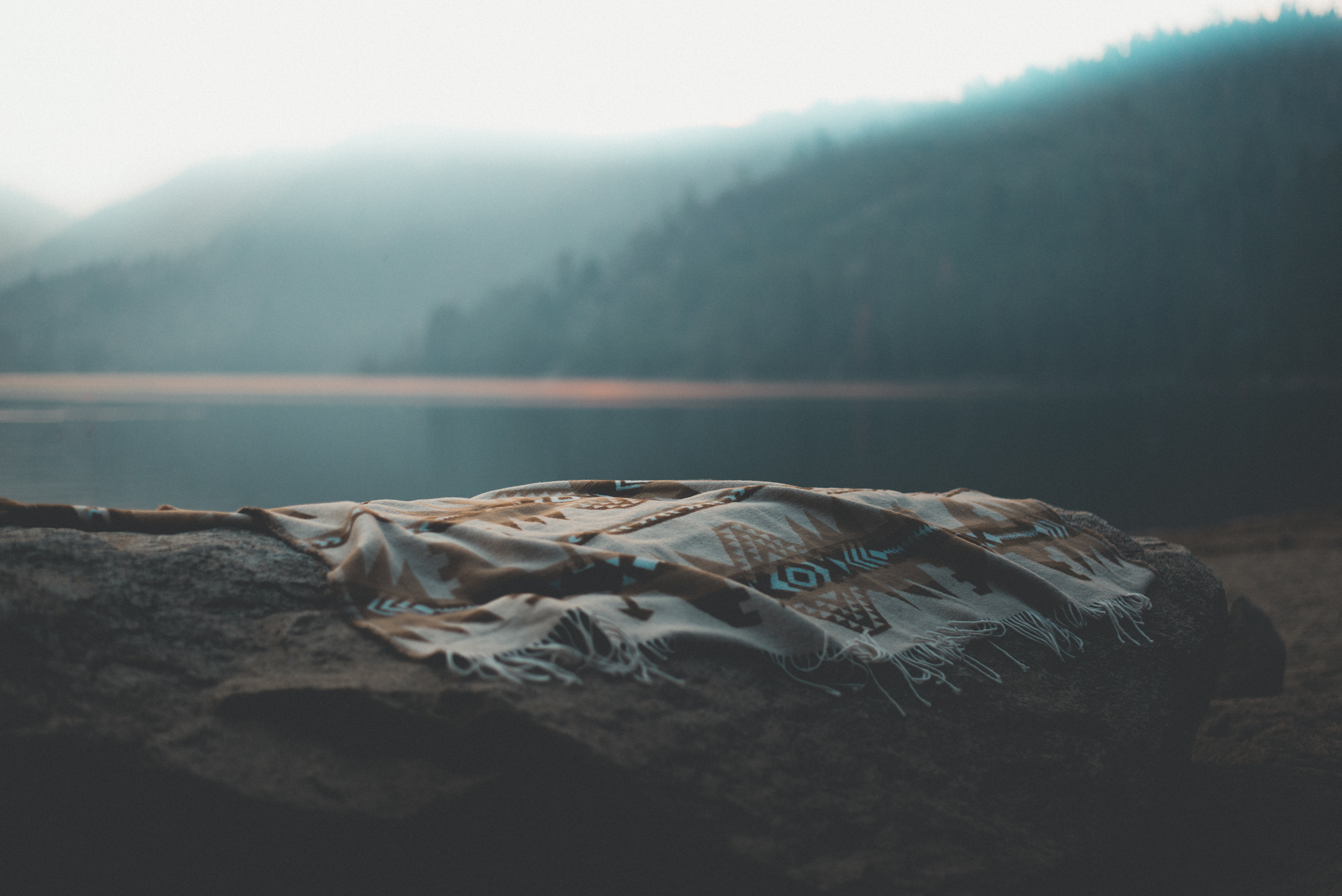 Blanket on a rock by a misty lake HD Wallpaper
