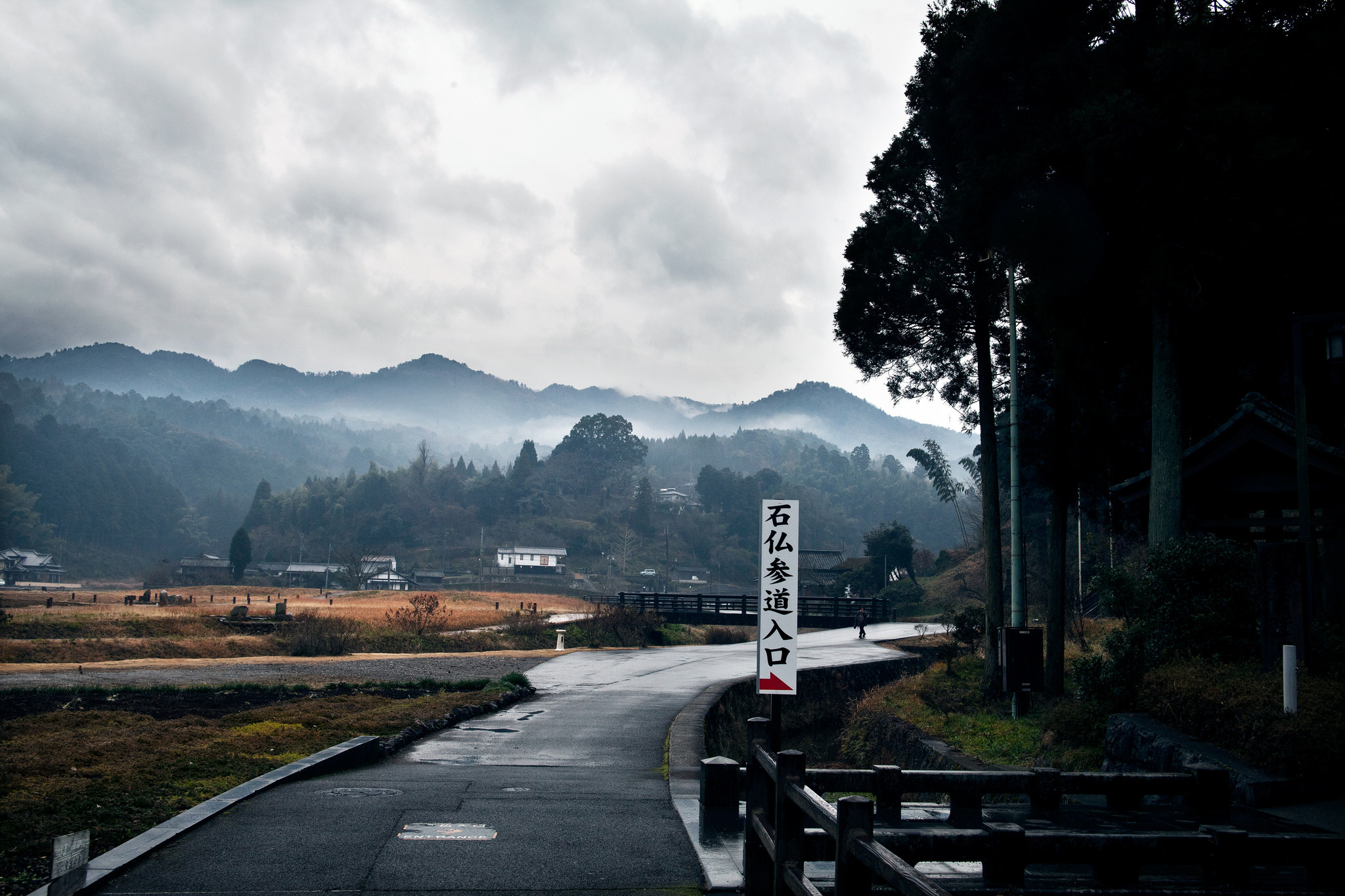 Road leading to misty mountains in a rural village HD Wallpaper