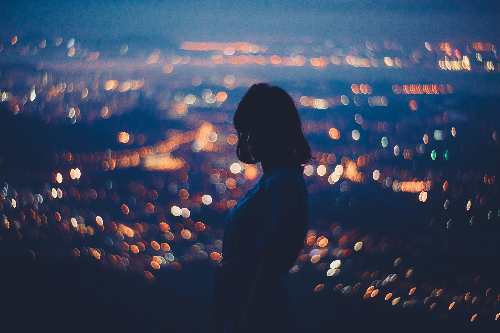 Silhouette of a woman against bokeh city lights HD Wallpaper