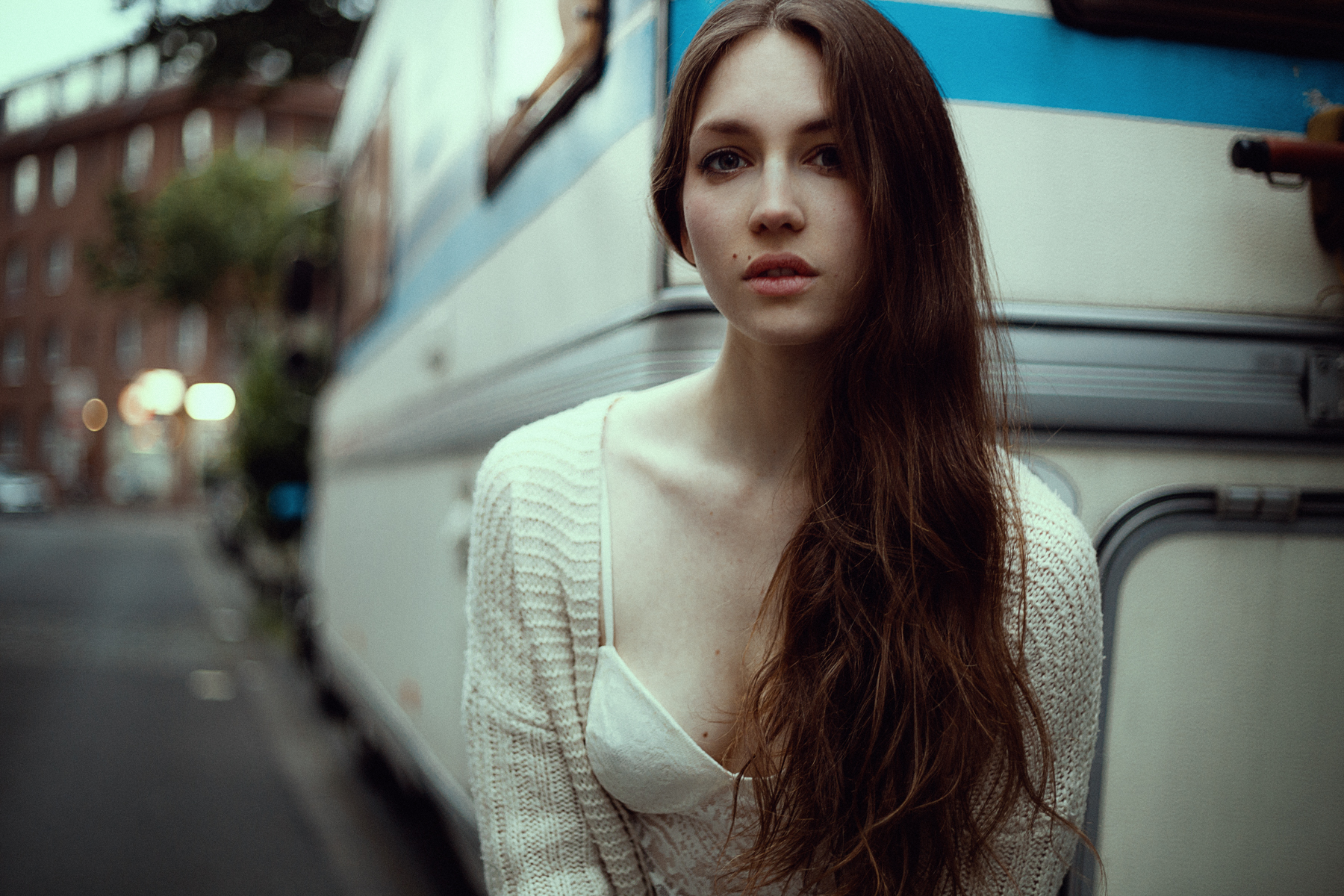 Woman in a white cardigan standing next to a camper HD Wallpaper