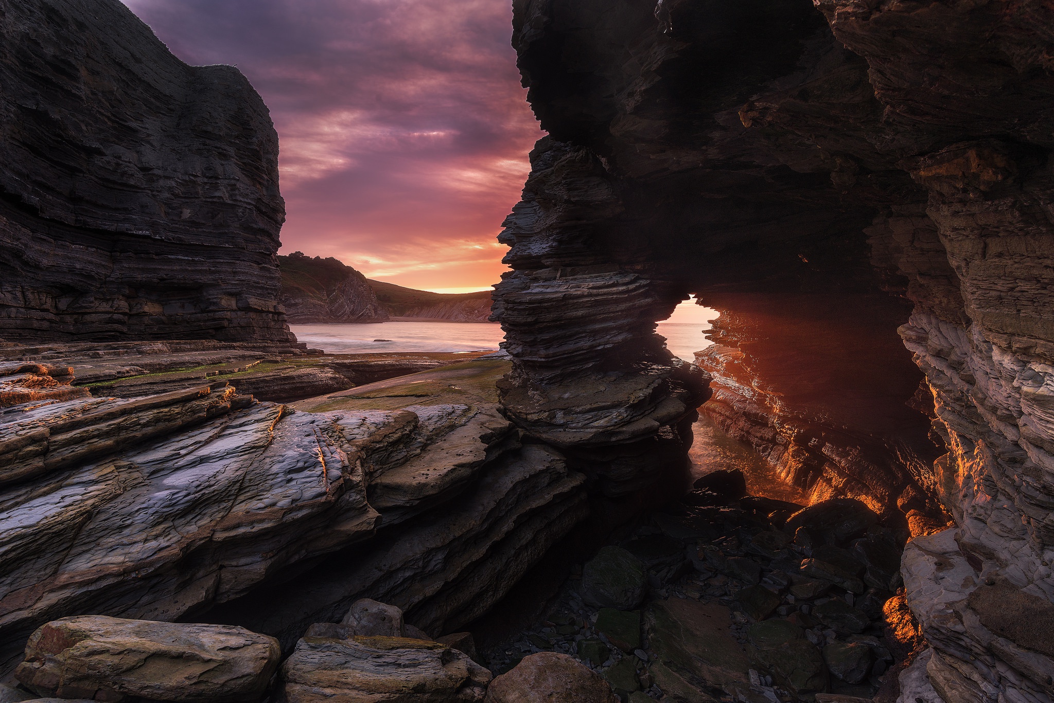 Rocky coastline with sea cave at sunset HD Wallpaper