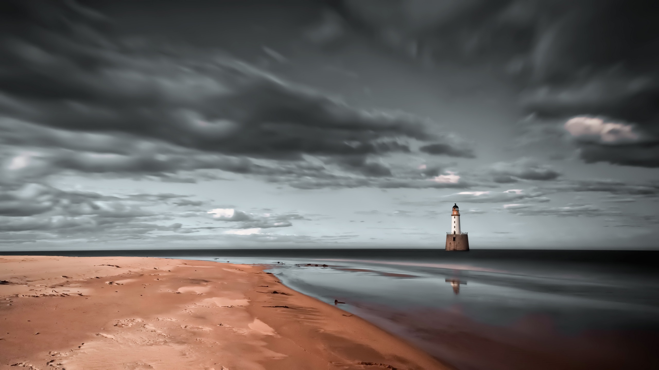 Lighthouse on the sea with beach and dark clouds HD Wallpaper