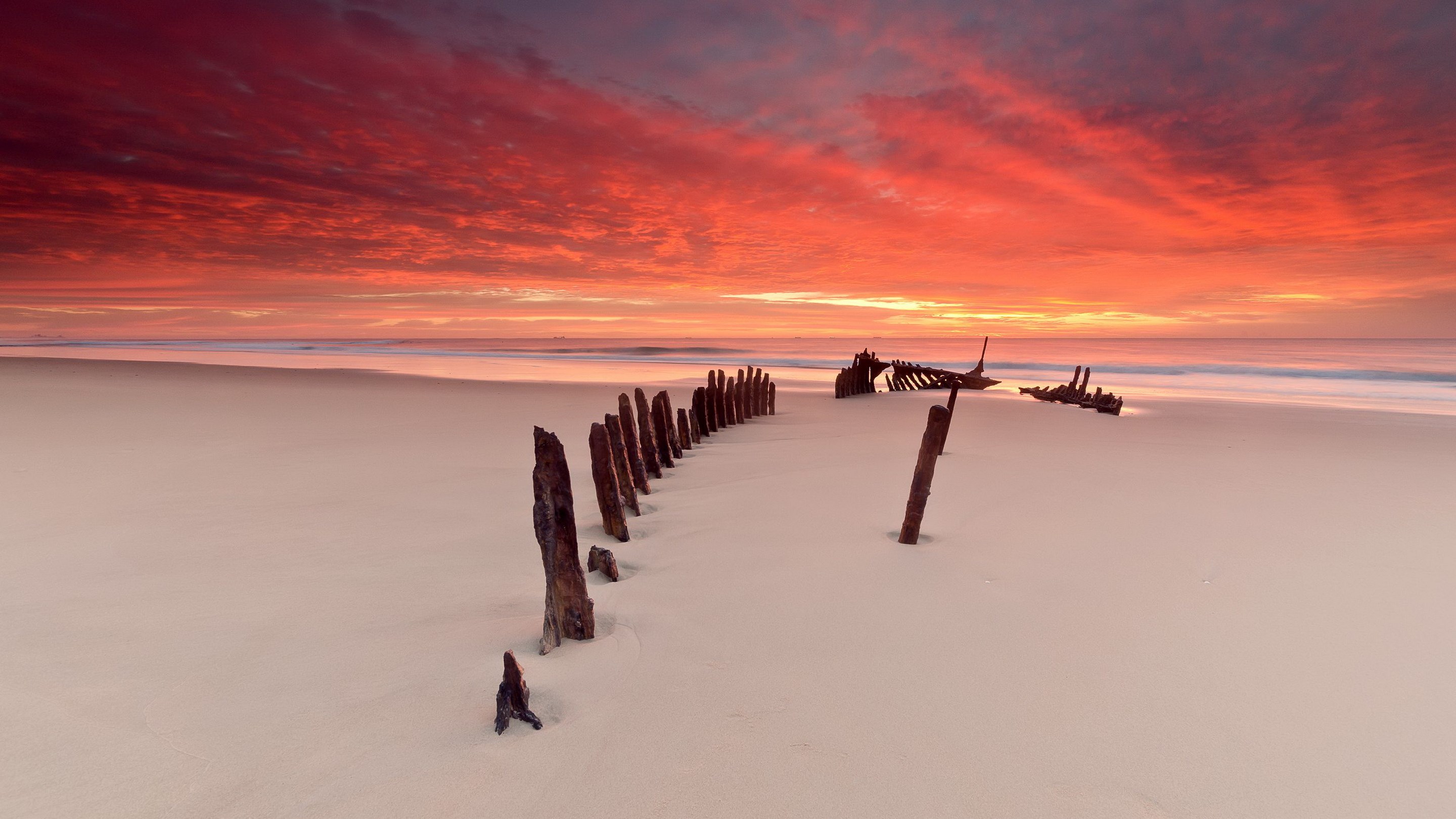 Shipwreck remains on a beach at sunset HD Wallpaper