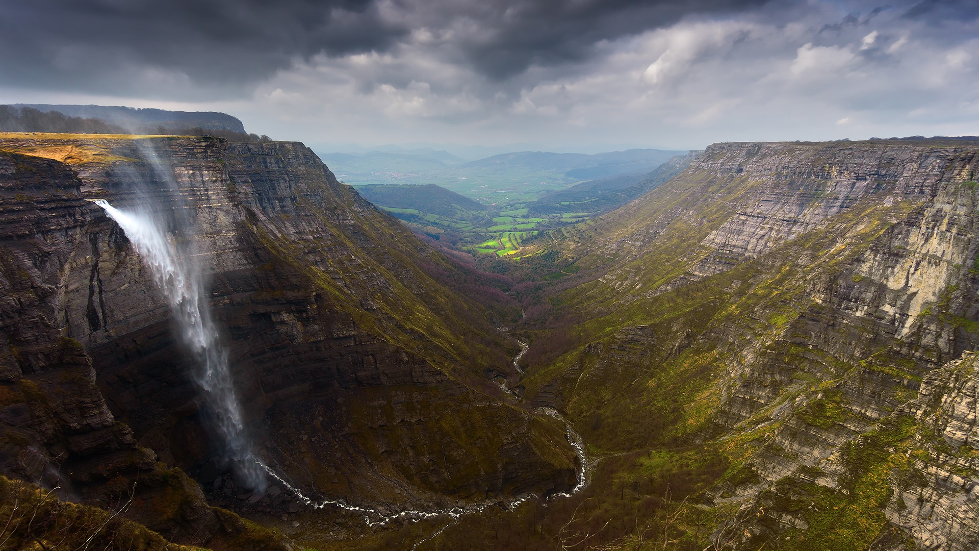 Waterfall cascading into a deep canyon valley HD Wallpaper