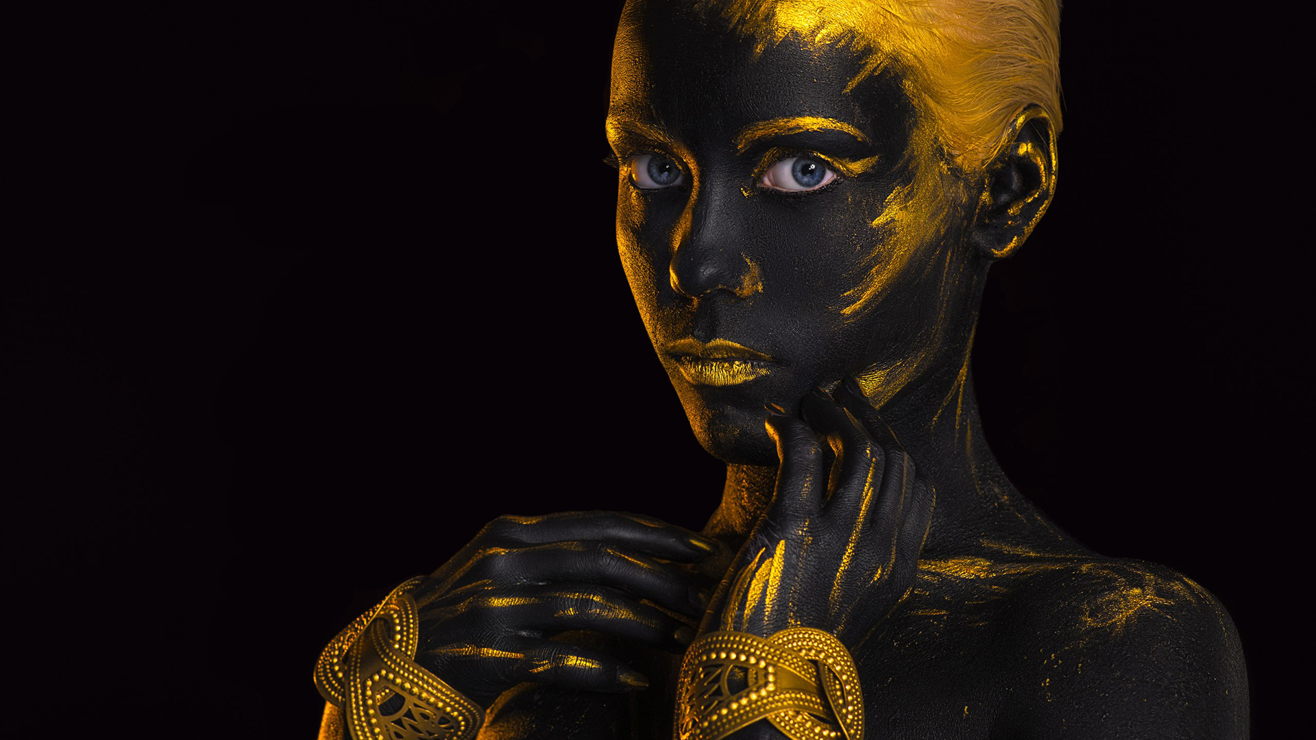 Woman with black and gold body paint and blue eyes HD Wallpaper
