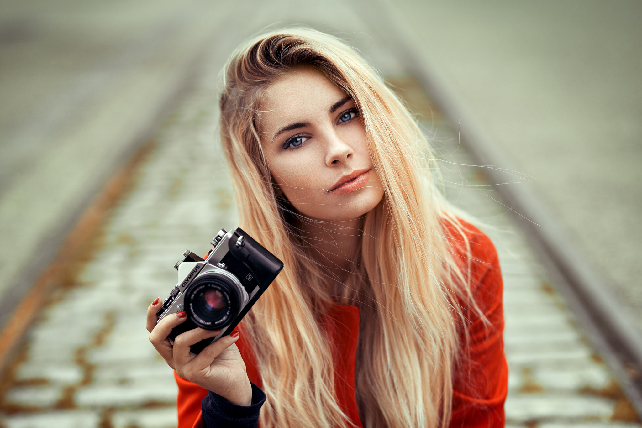 Woman with blonde hair holding an Olympus camera HD Wallpaper