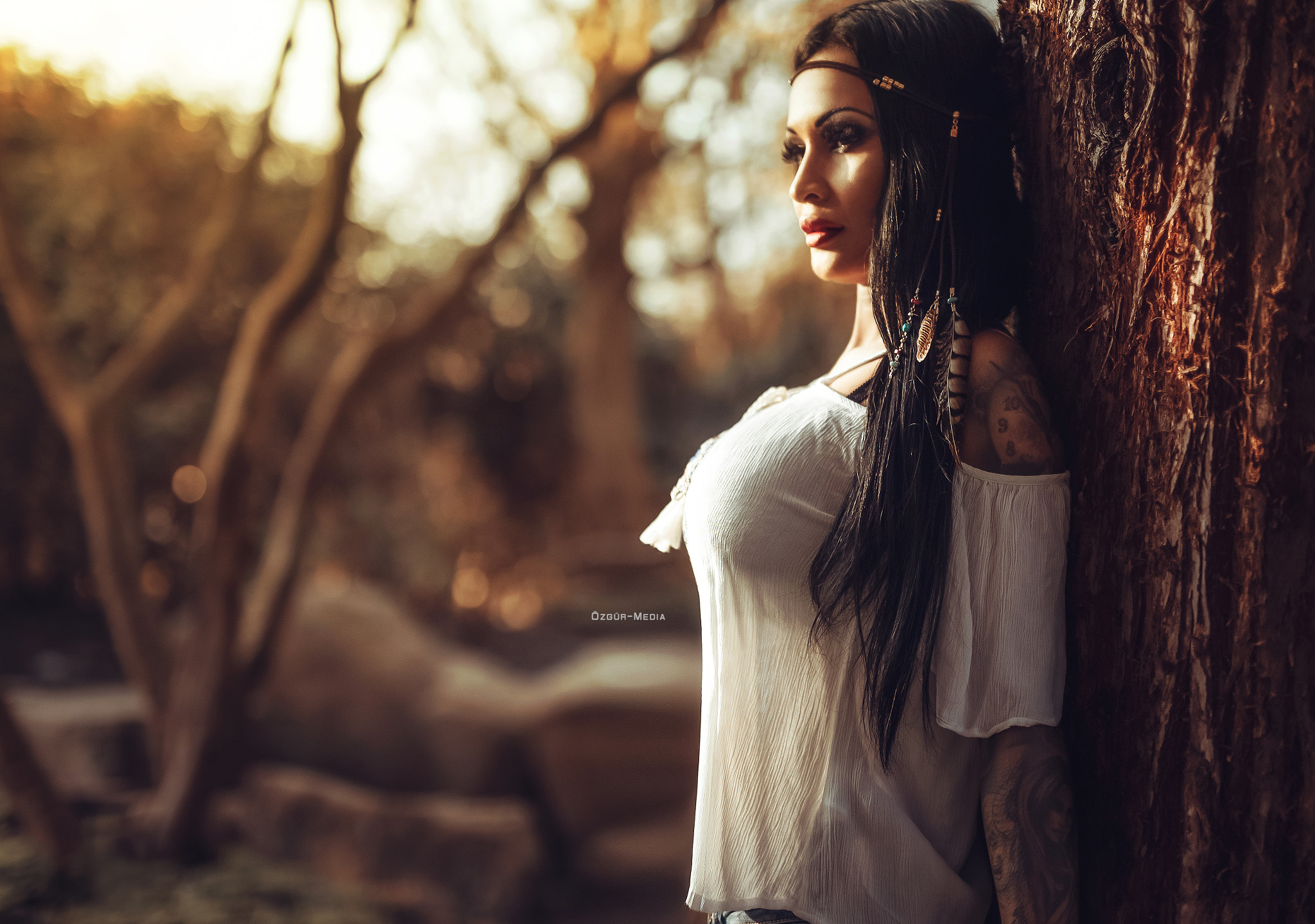 Woman with tattoos and hair beads leaning against a tree HD Wallpaper