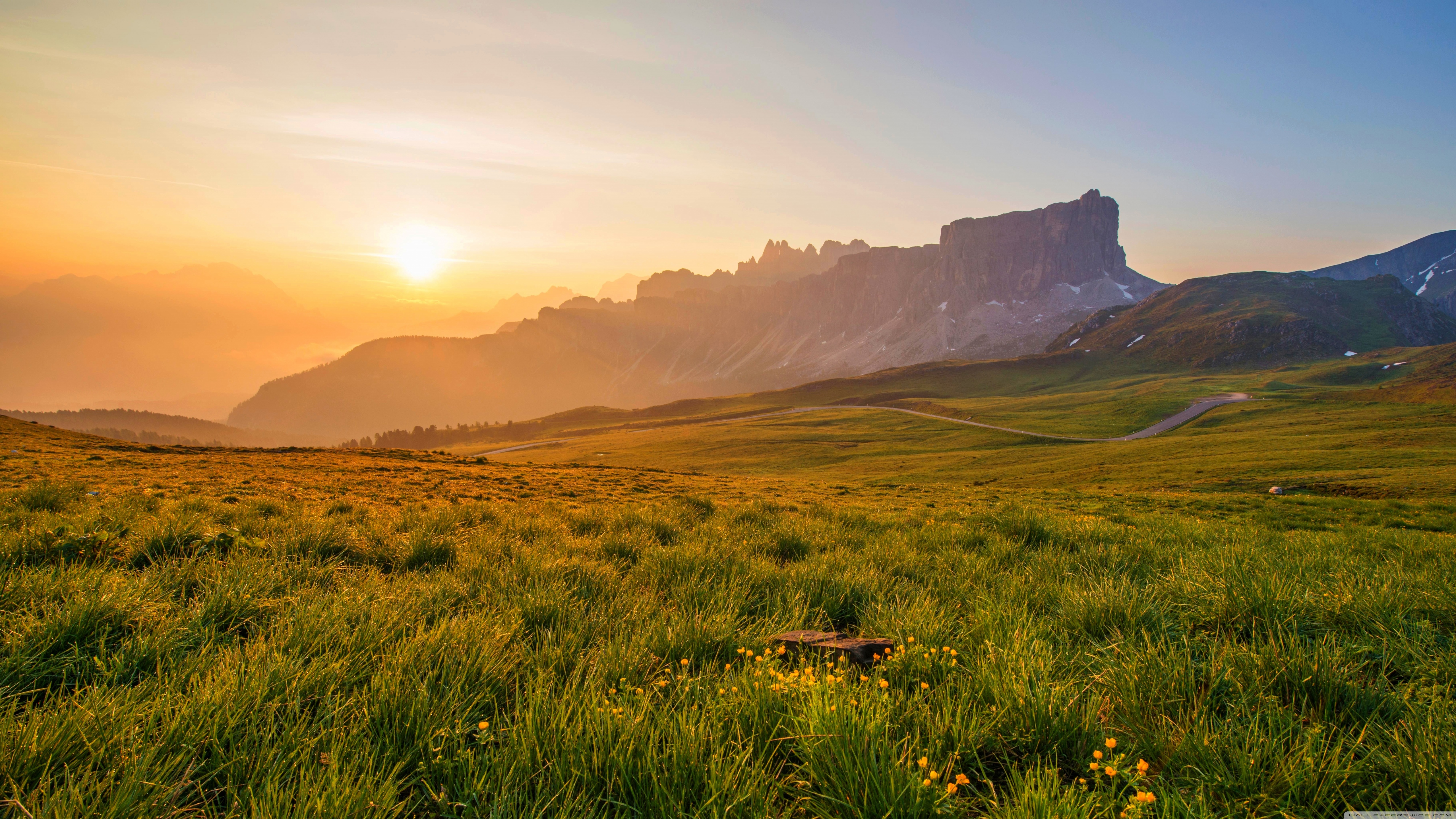 Sunrise over a mountain valley with green fields HD Wallpaper