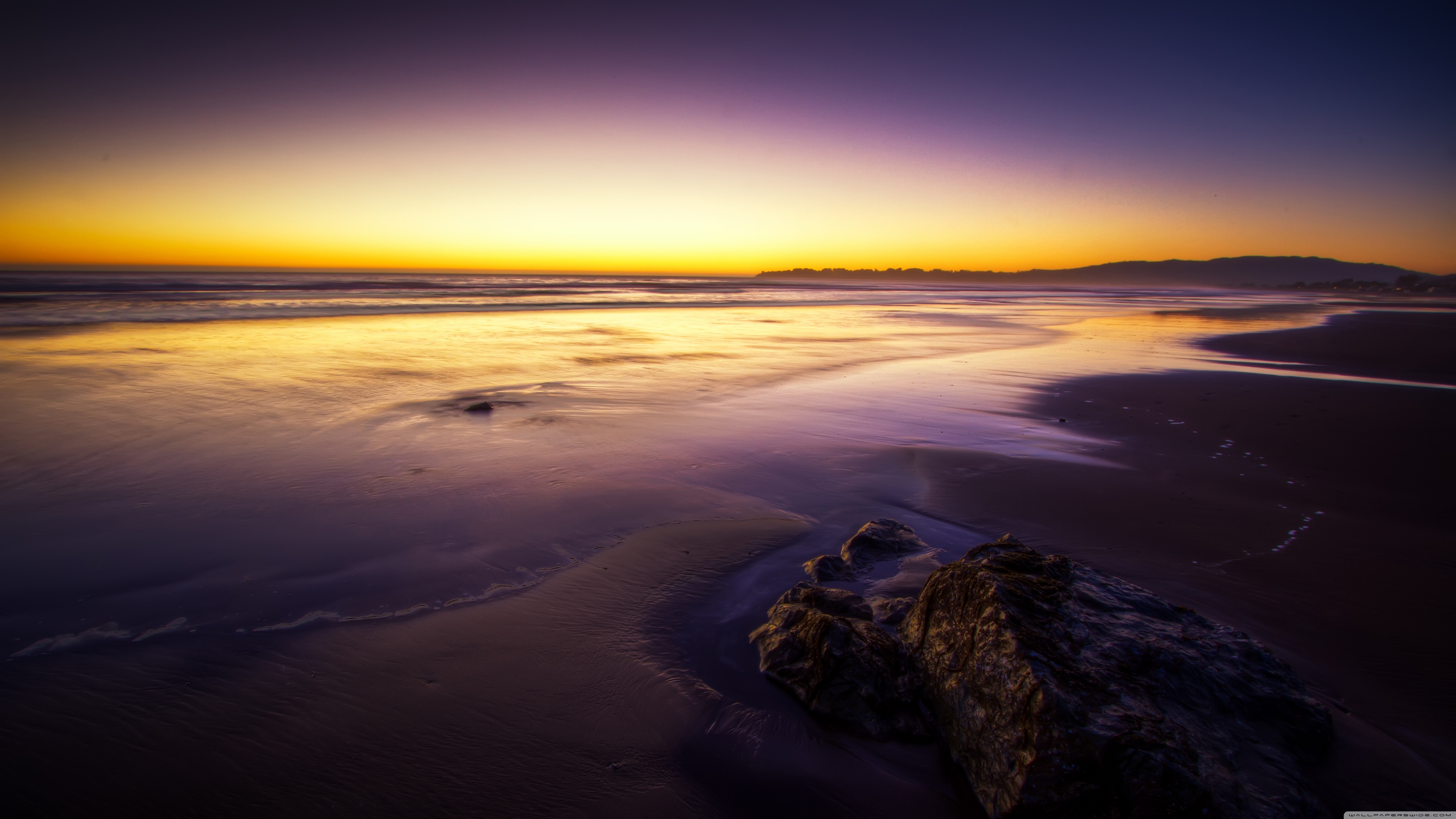 Sunset over a beach with rocks HD Wallpaper