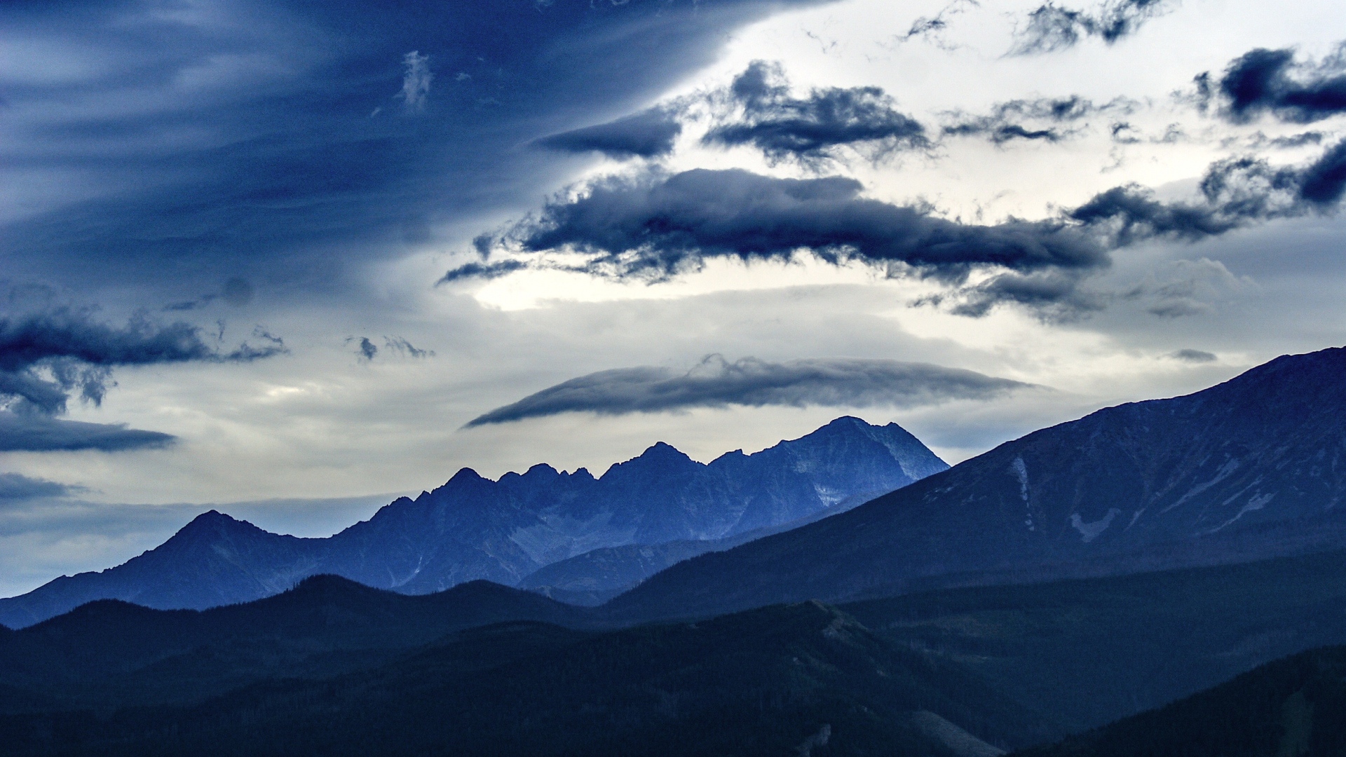 Dark stormy clouds over blue mountain ranges HD Wallpaper