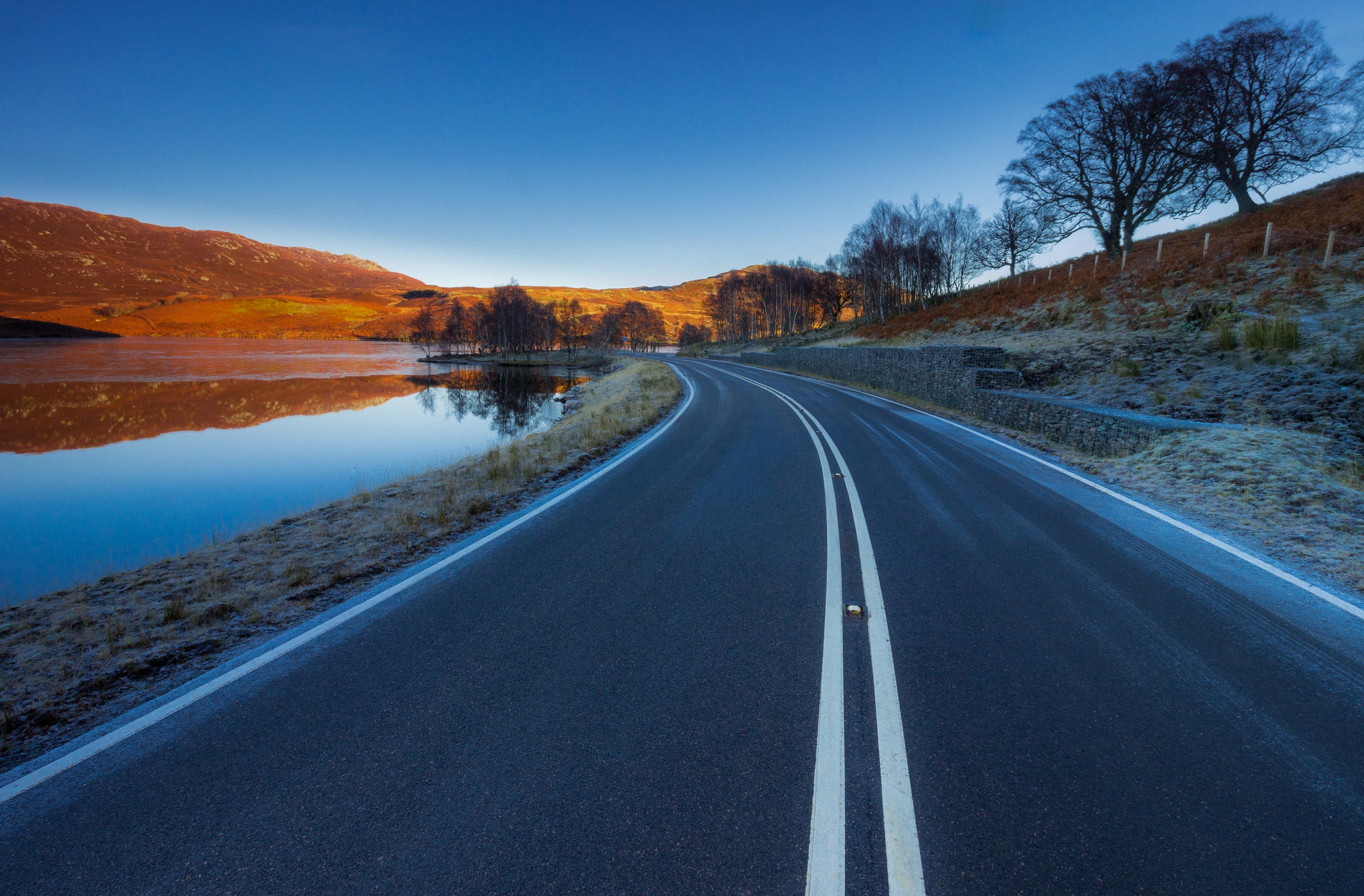 Curving road through a winter landscape with a lake HD Wallpaper