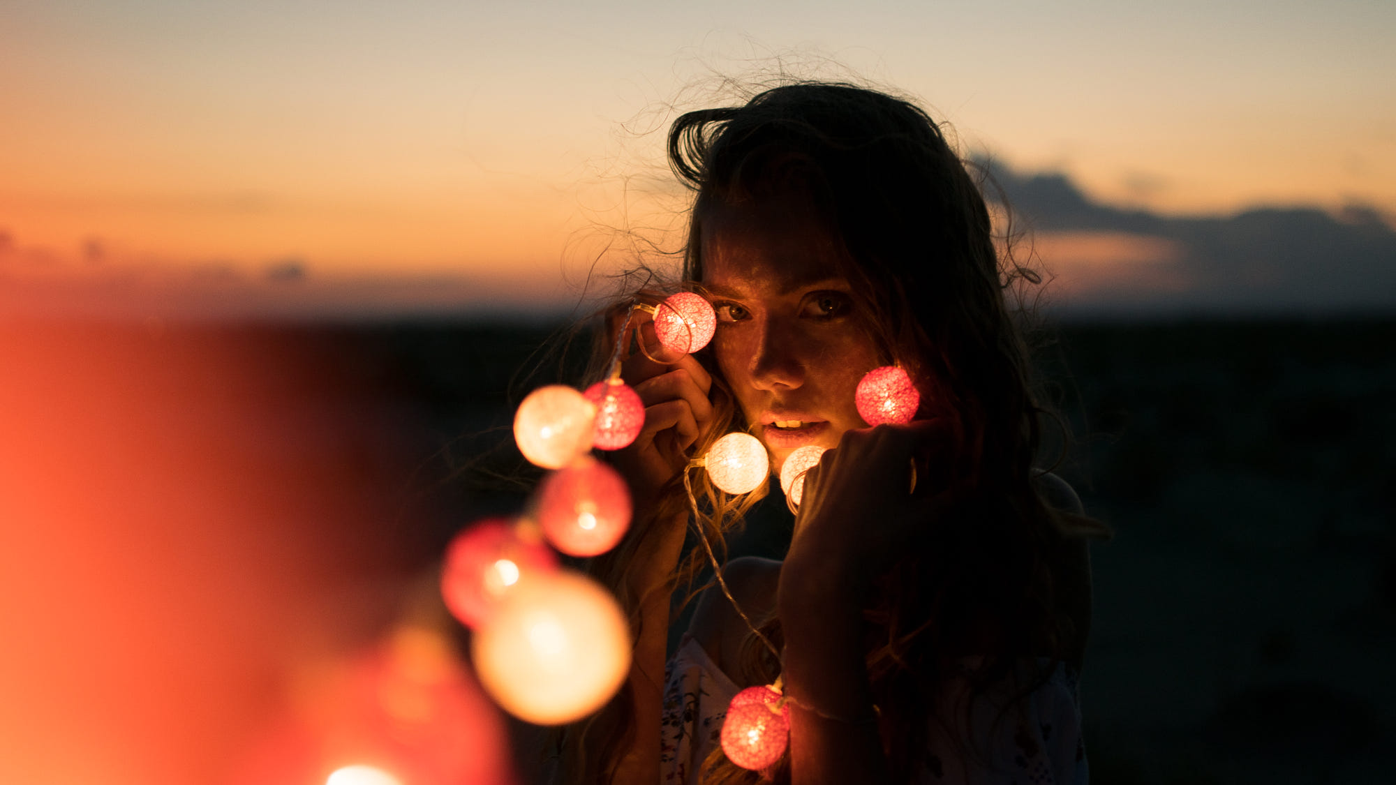 Woman with string lights at sunset HD Wallpaper
