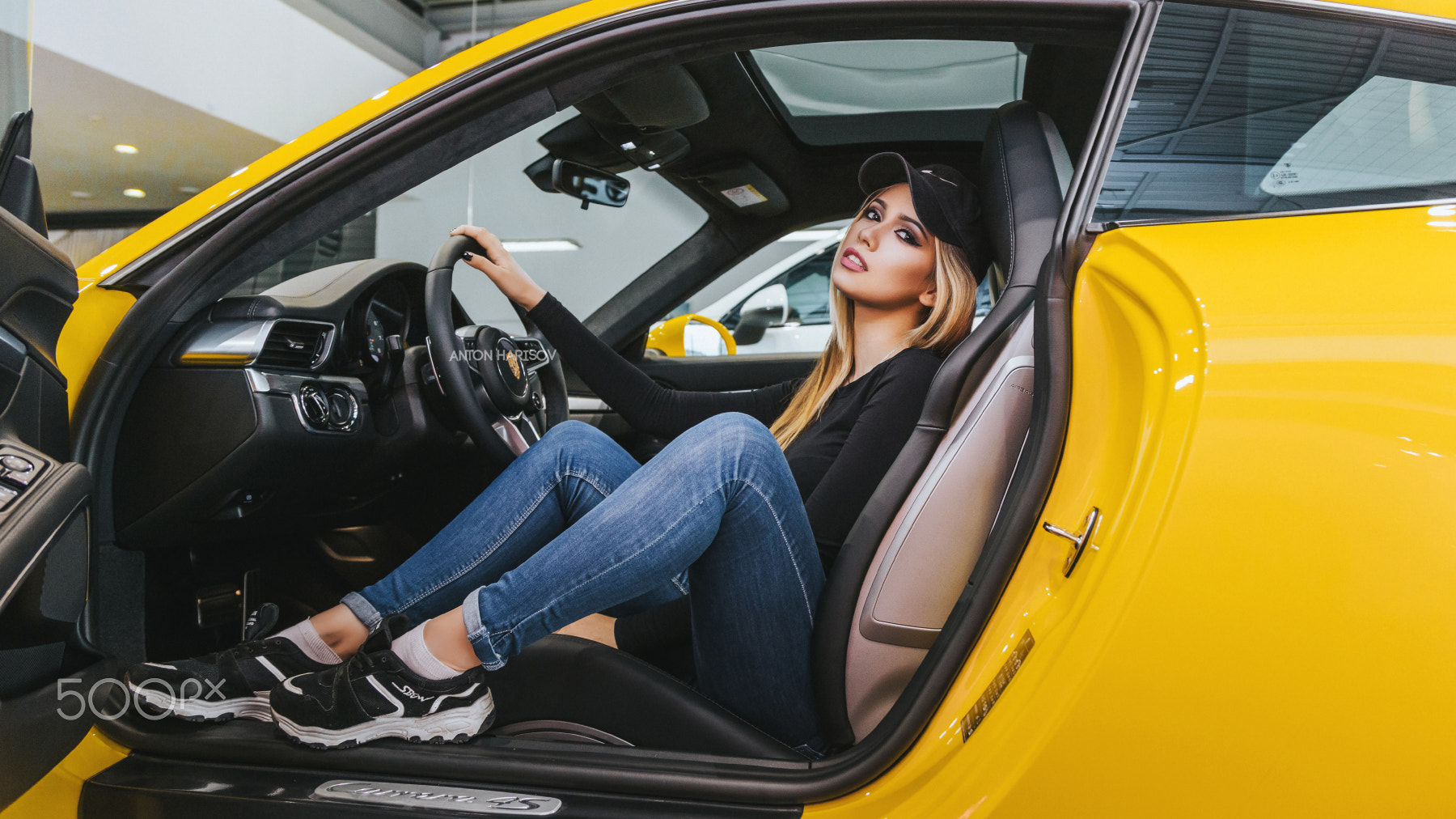 Woman in jeans and sneakers sitting in a yellow car HD Wallpaper
