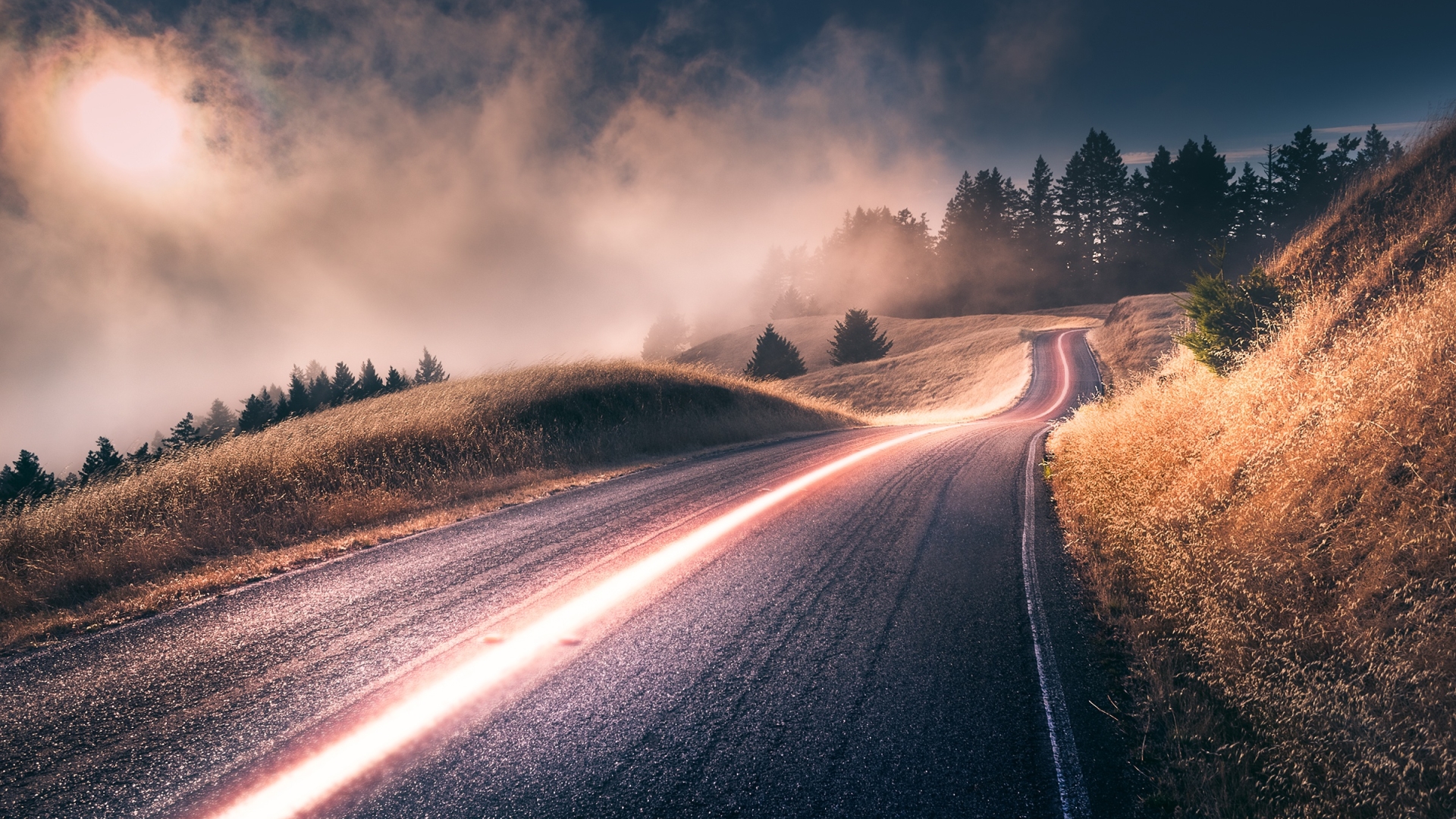 Road through misty hills with light trails HD Wallpaper