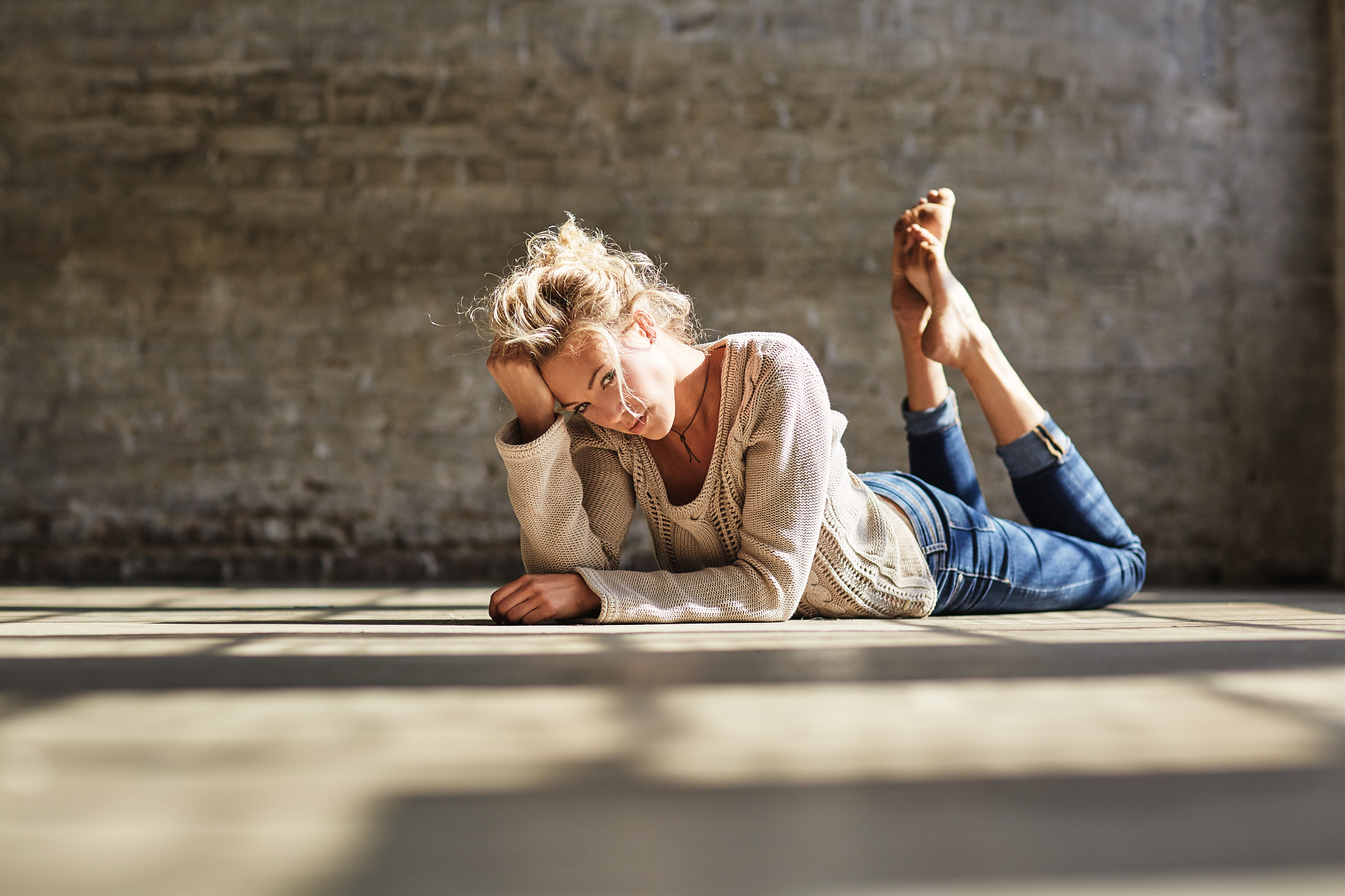 Woman in jeans and sweater lying on floor HD Wallpaper