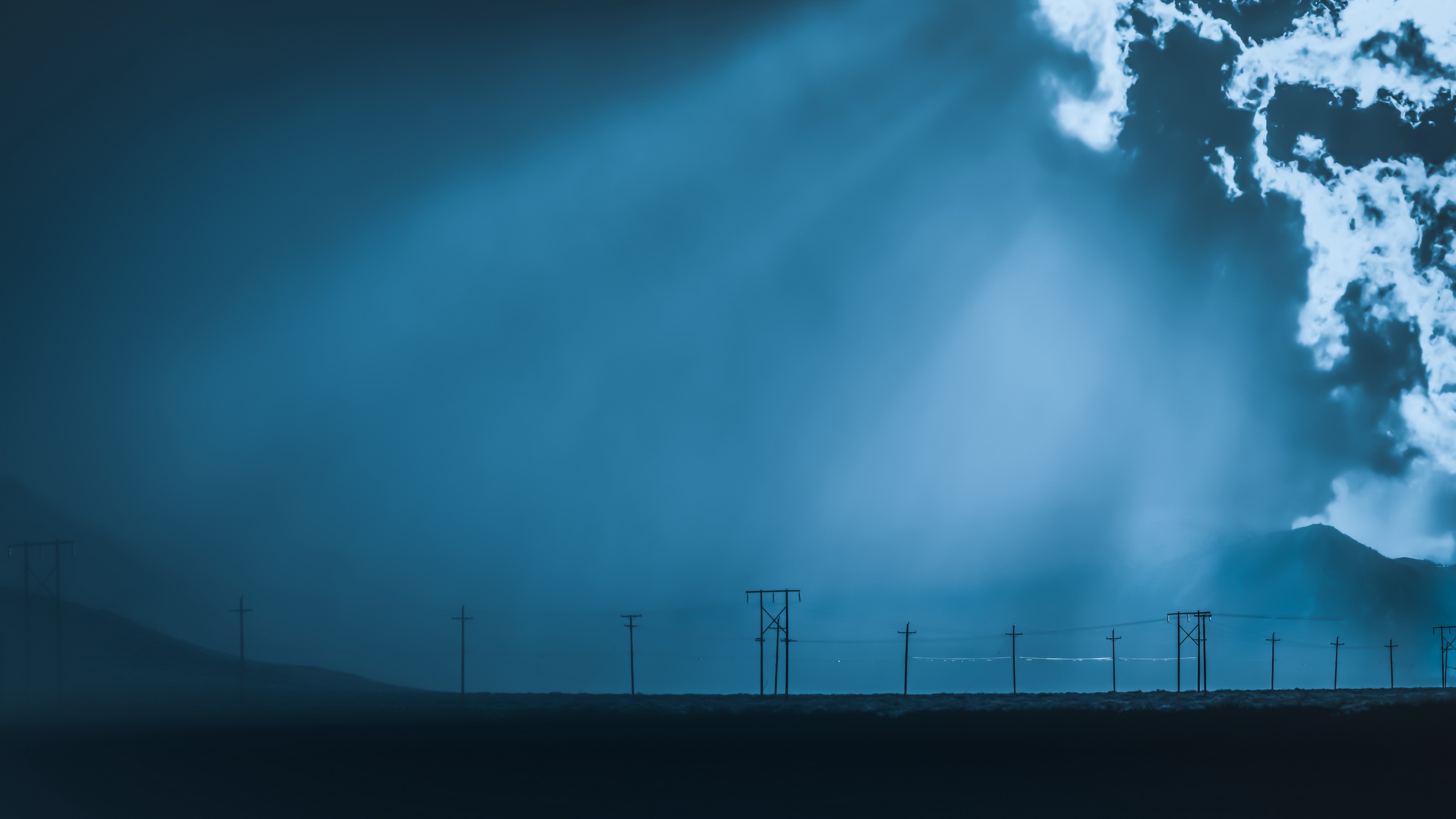 Power lines in a foggy blue landscape with sunbeams HD Wallpaper