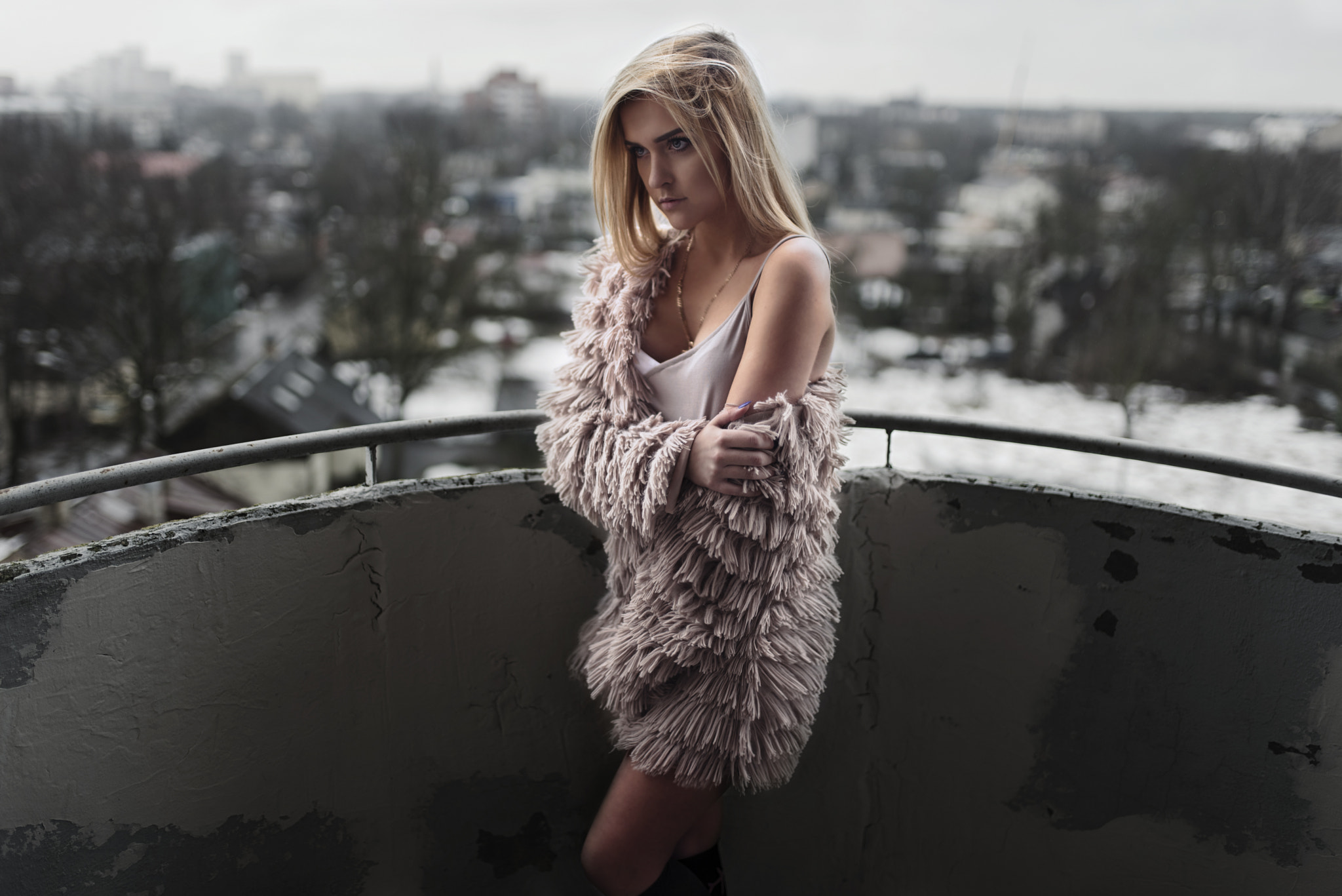 Woman in fluffy coat on a balcony overlooking city HD Wallpaper