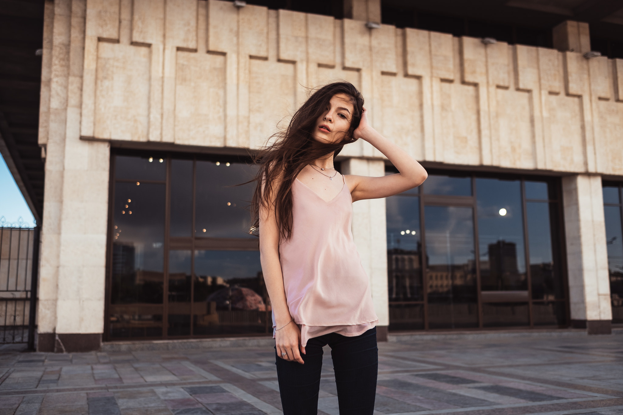 Woman with hands in hair in front of building HD Wallpaper